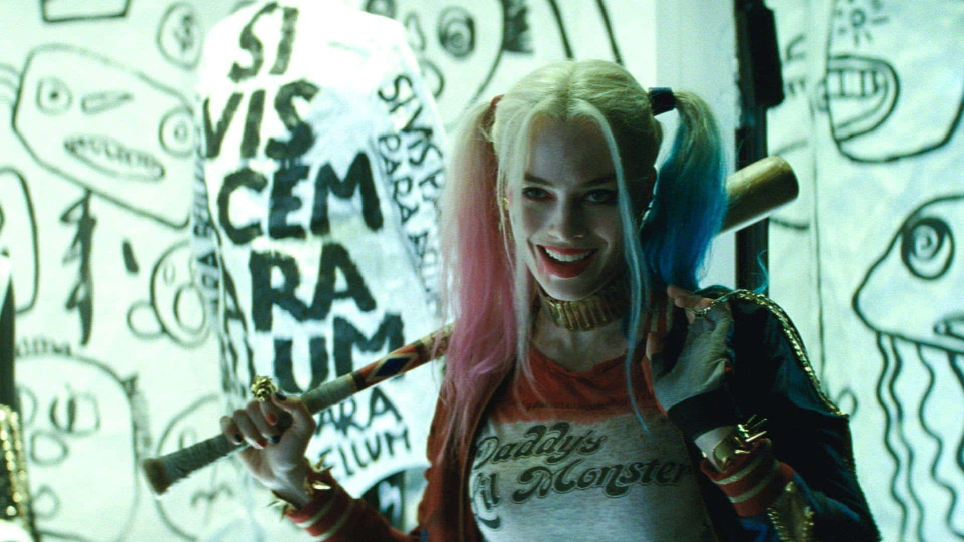 The Suicide Squad 桌布 壁紙 — 哈莉·奎茵咧嘴狂笑，手持棒球棍，面向一面佈滿塗鴉、混亂塗鴉和拉丁文字的牆壁。