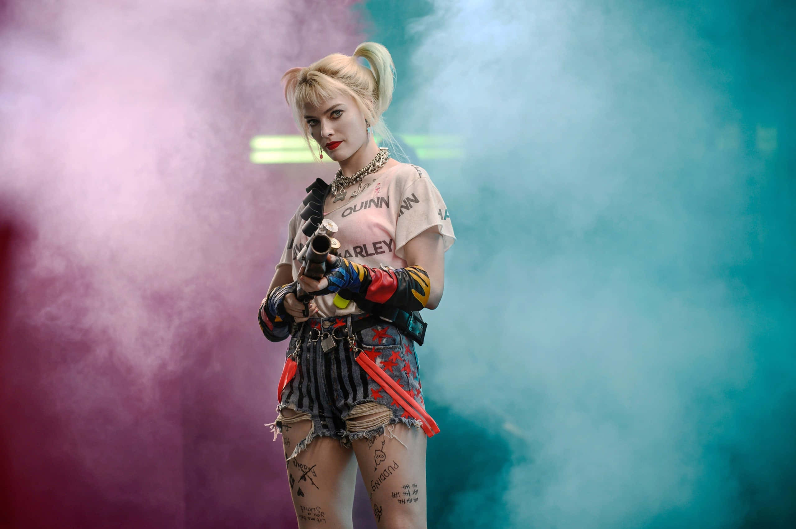 Harley Quinn Suicide Squad 桌布 壁紙 — 哈莉·奎茵自信地站在煙霧瀰漫的環境中，粉紅色和青綠色的燈光下，手持武器，穿著她標誌性的混亂服裝。