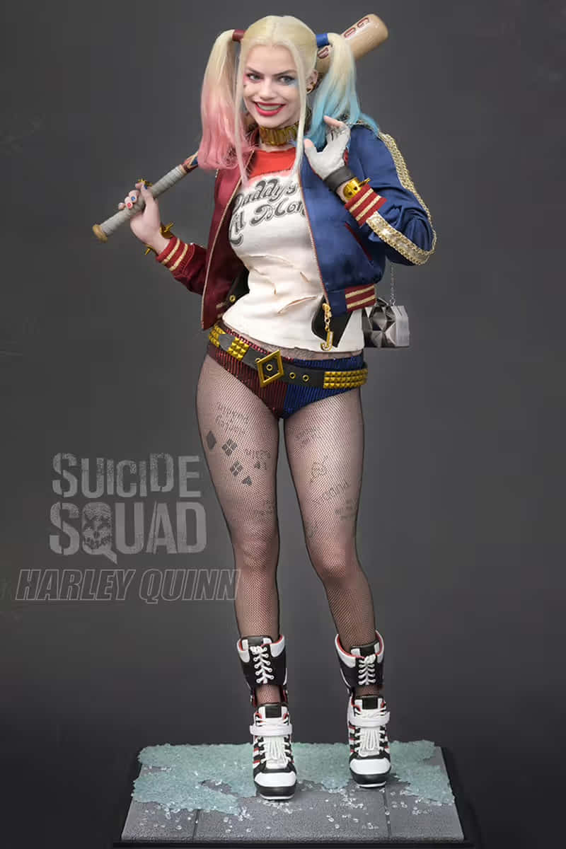Harley Quinn Cosplay 桌布 壁紙 — 哈莉·奎茵雕像身穿全套服裝，在深灰色工作室背景前手持棒球棍。