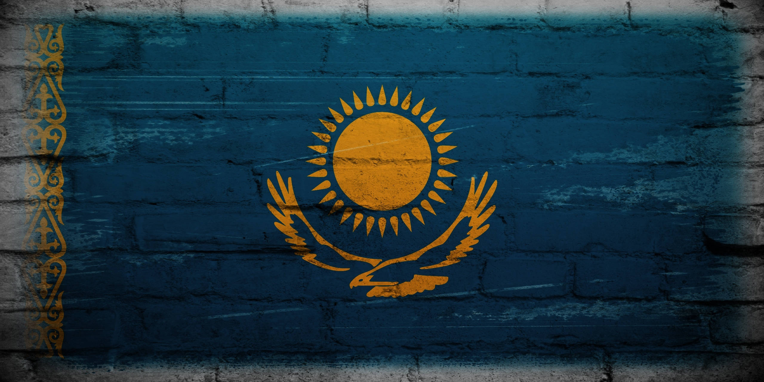 Kazakhstan 桌布 壁紙 — 哈薩克國旗以鮮豔的黃色和藍色繪製在風化的磚牆上，帶有紋理筆觸。