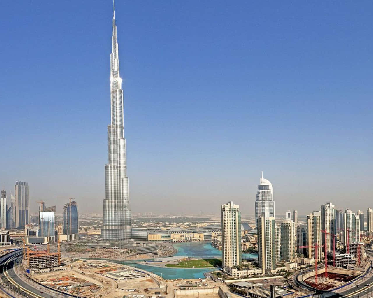 Burj Khalifa 桌布 壁紙 — 哈里發塔在晴朗的藍天下聳立於杜拜的天際線，周圍環繞著現代摩天大樓和建築工地。