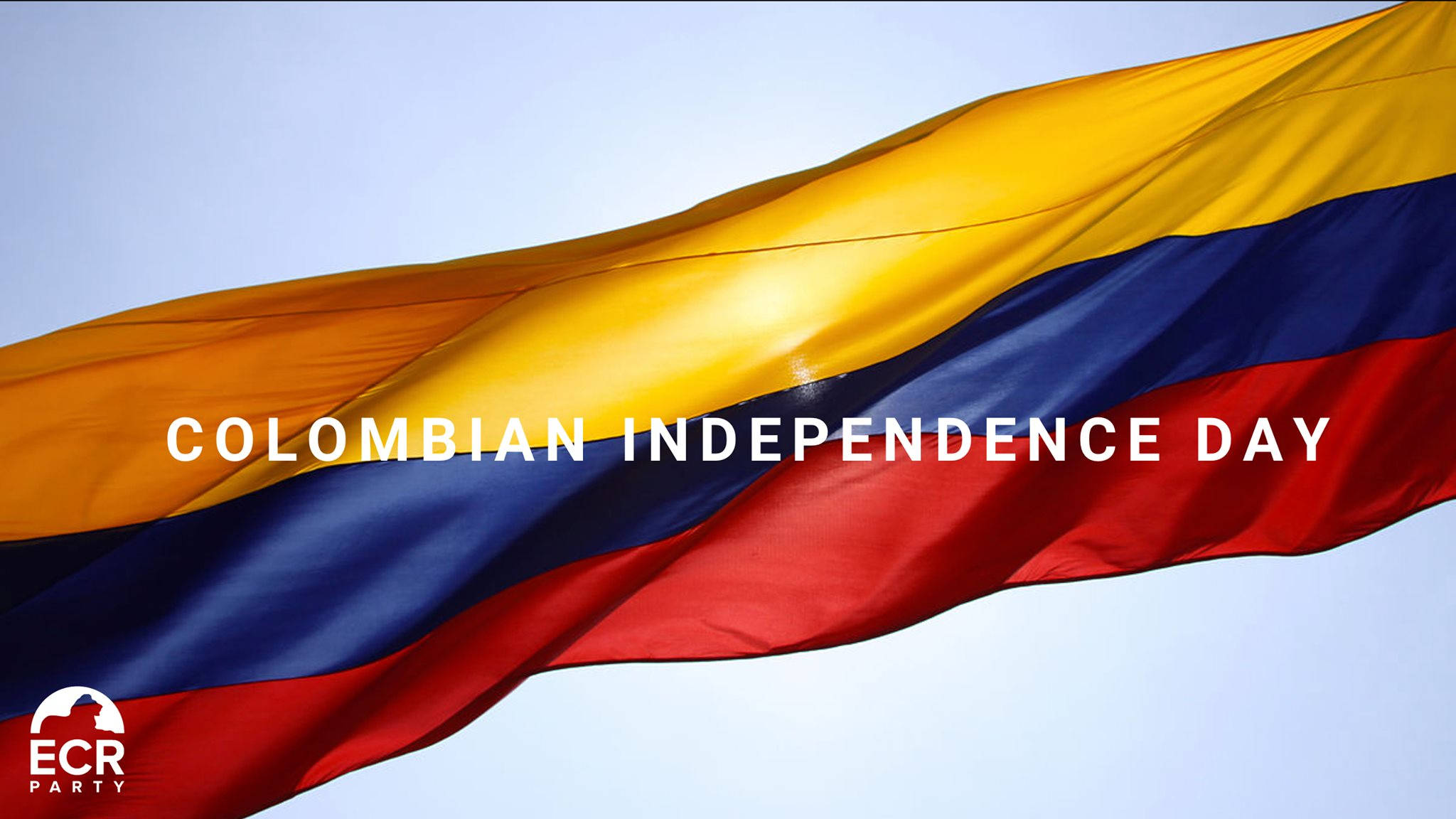Independence 桌布 壁紙 — 哥倫比亞國旗在晴朗的天空下動態飄揚，帶有鮮明的黃、藍、紅條紋和慶祝獨立日的文字。