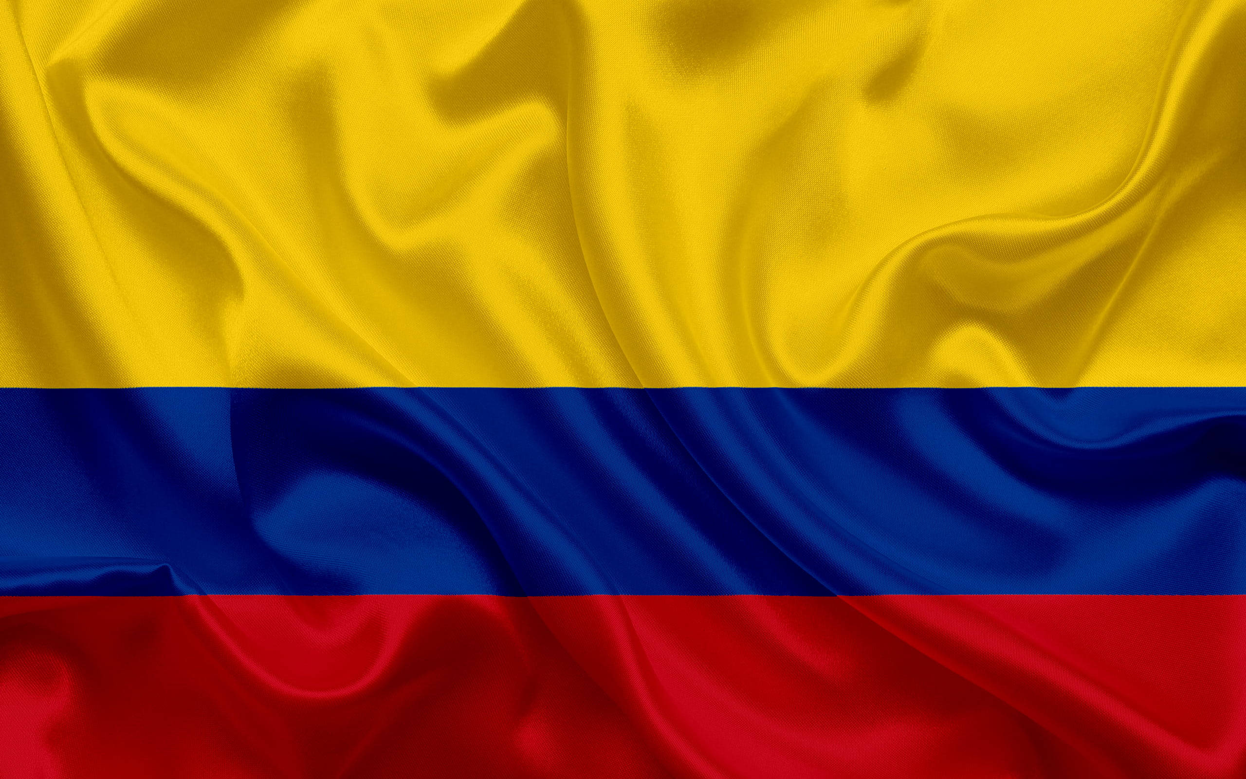Colombia Flag 桌布 壁紙 — 哥倫比亞國旗的特寫，鮮豔的黃色、藍色和紅色條紋在柔軟的布料褶皺中飄動。