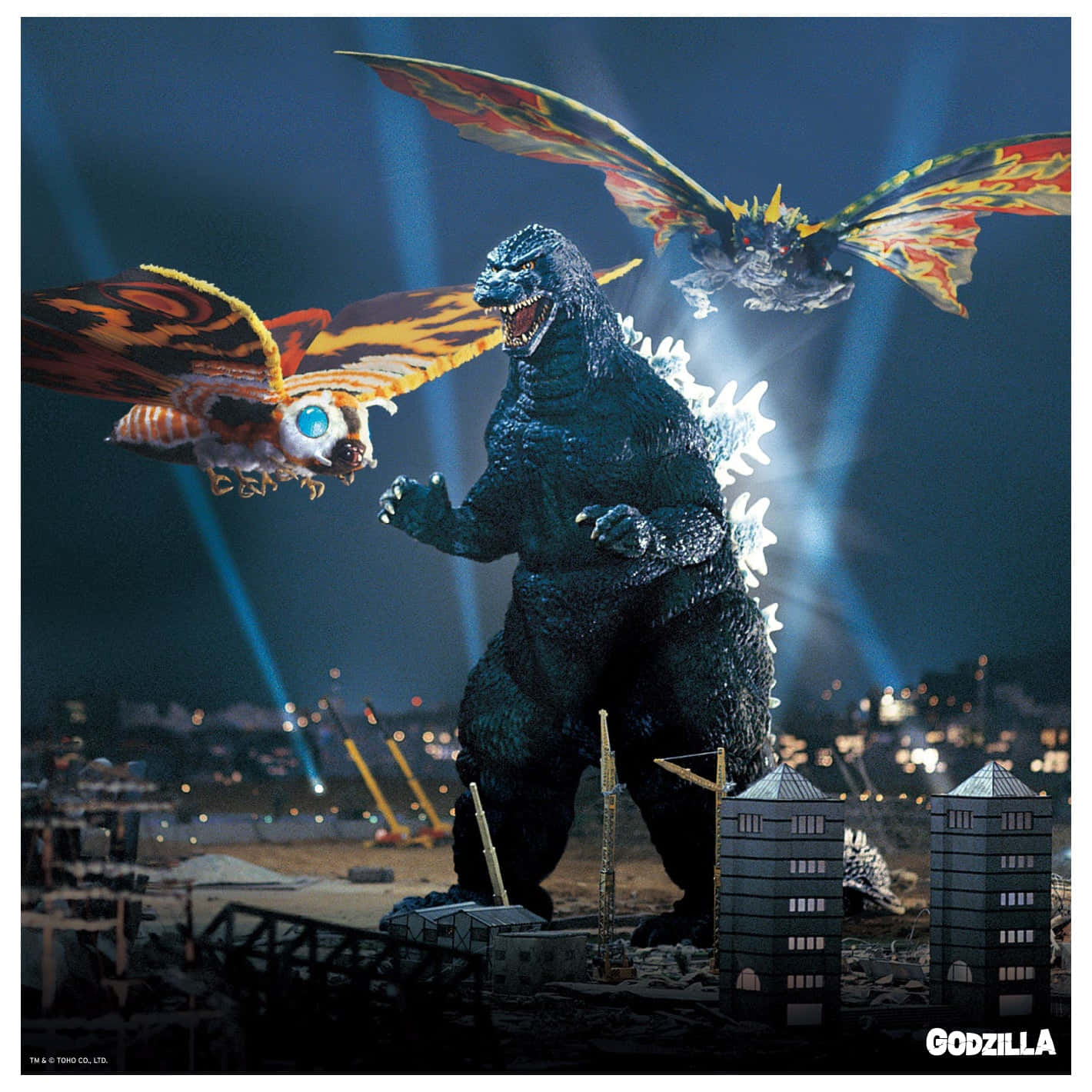Godzilla Vs Mothra 桌布 壁紙 — 哥吉拉在夜晚站在被毀滅的城市建築物中，兩隻巨大的有翼怪物在上空盤旋，眼睛發光，翅膀燃燒。