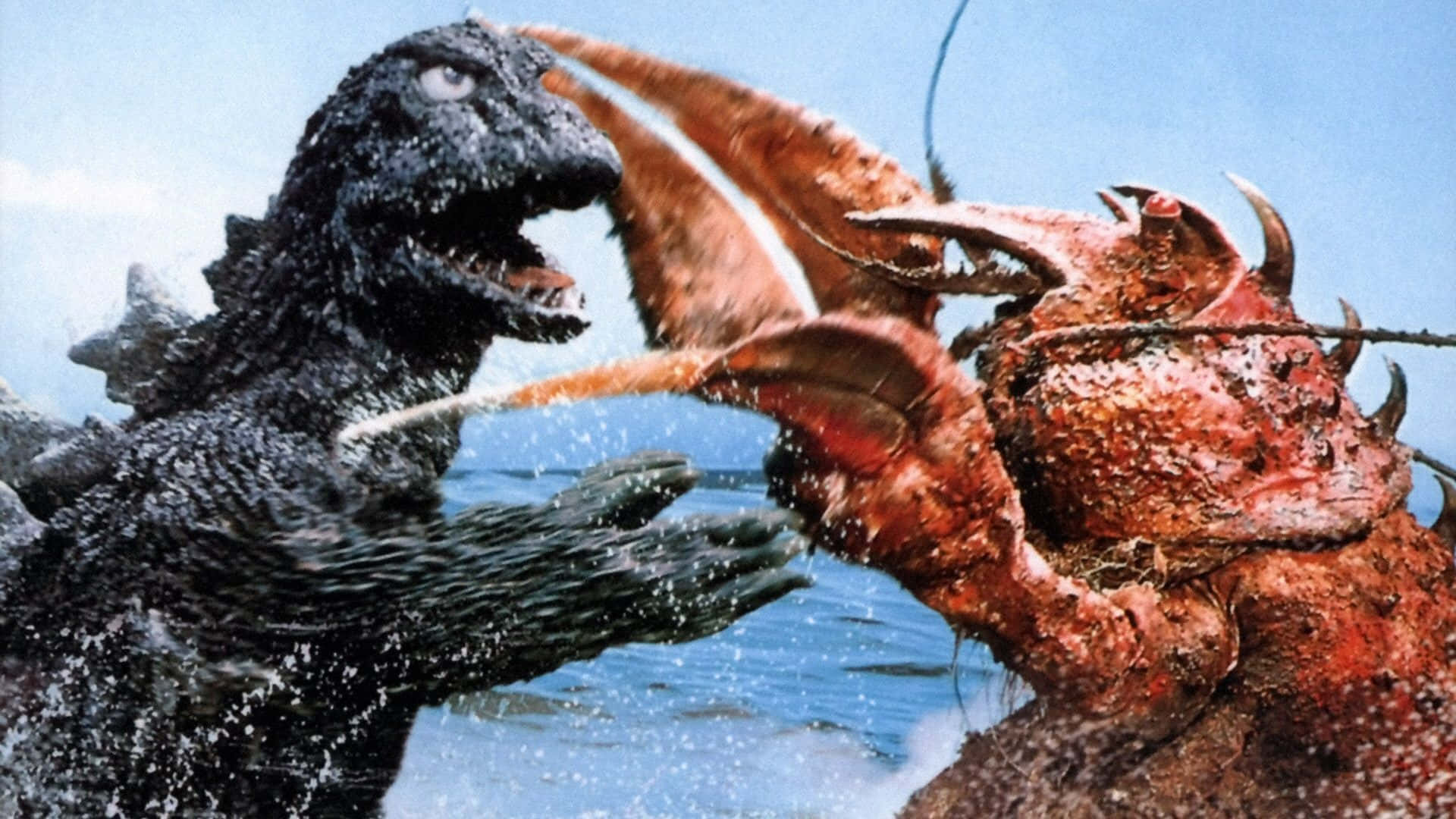 Classic Godzilla 桌布 壁紙 — 哥吉拉在晴朗的天空下，在濺起水花的藍色海水中與一隻巨大的紅色螃蟹狀怪物戰鬥。