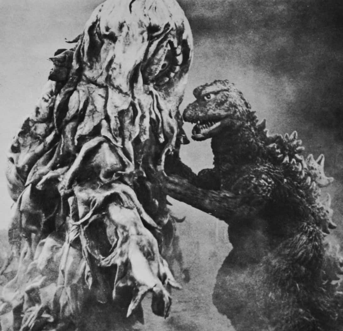 Godzilla Vs Hedorah 桌布 壁紙 — 哥吉拉在煙霧瀰漫的黑白電影對決中，面對一個怪誕、有紋理的怪物。