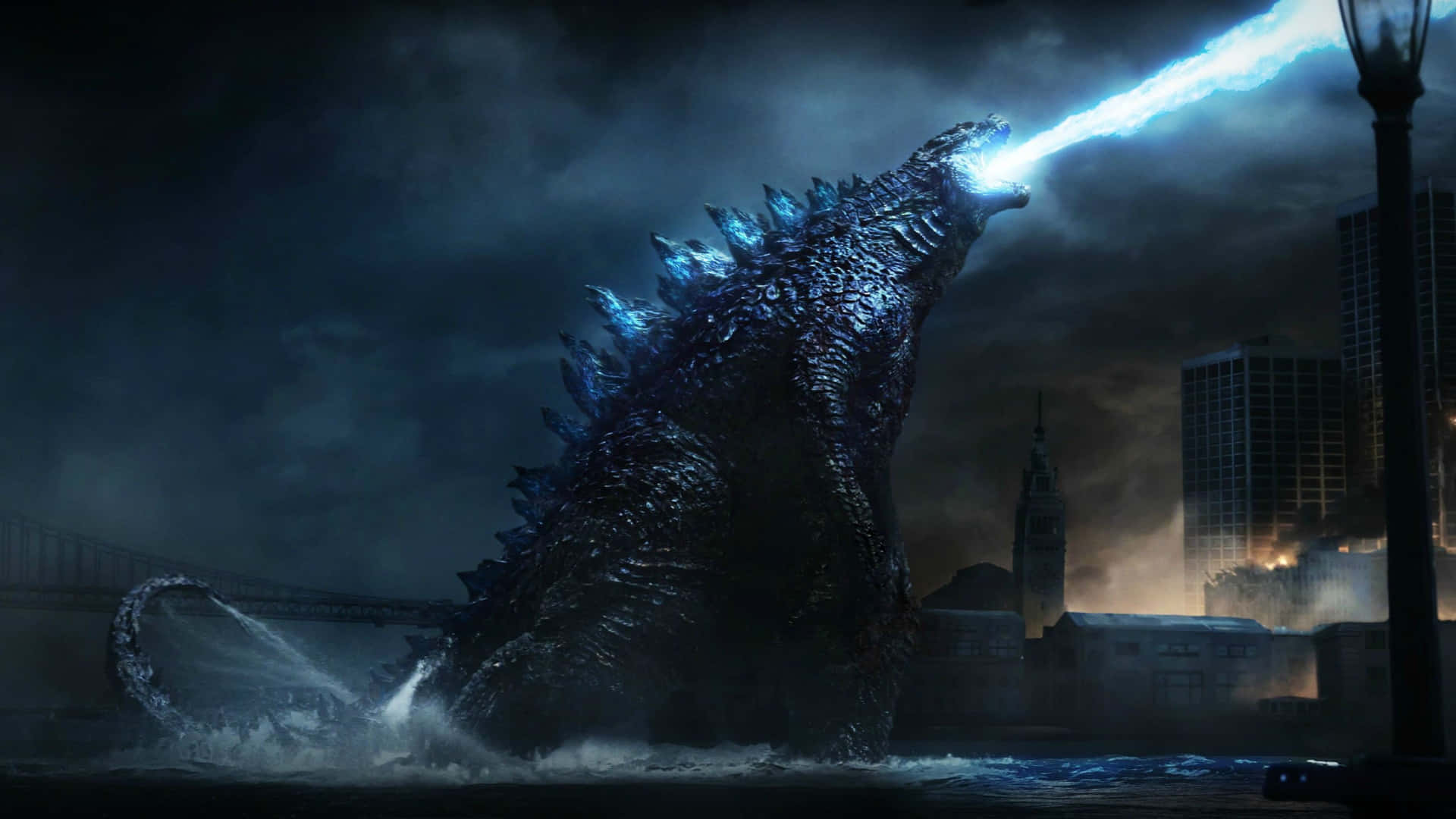 Godzilla City Destruction 桌布 壁紙 — 哥吉拉從黑暗城市景觀的水中出現，在暴風雨的天空下發射明亮的藍色原子吐息。