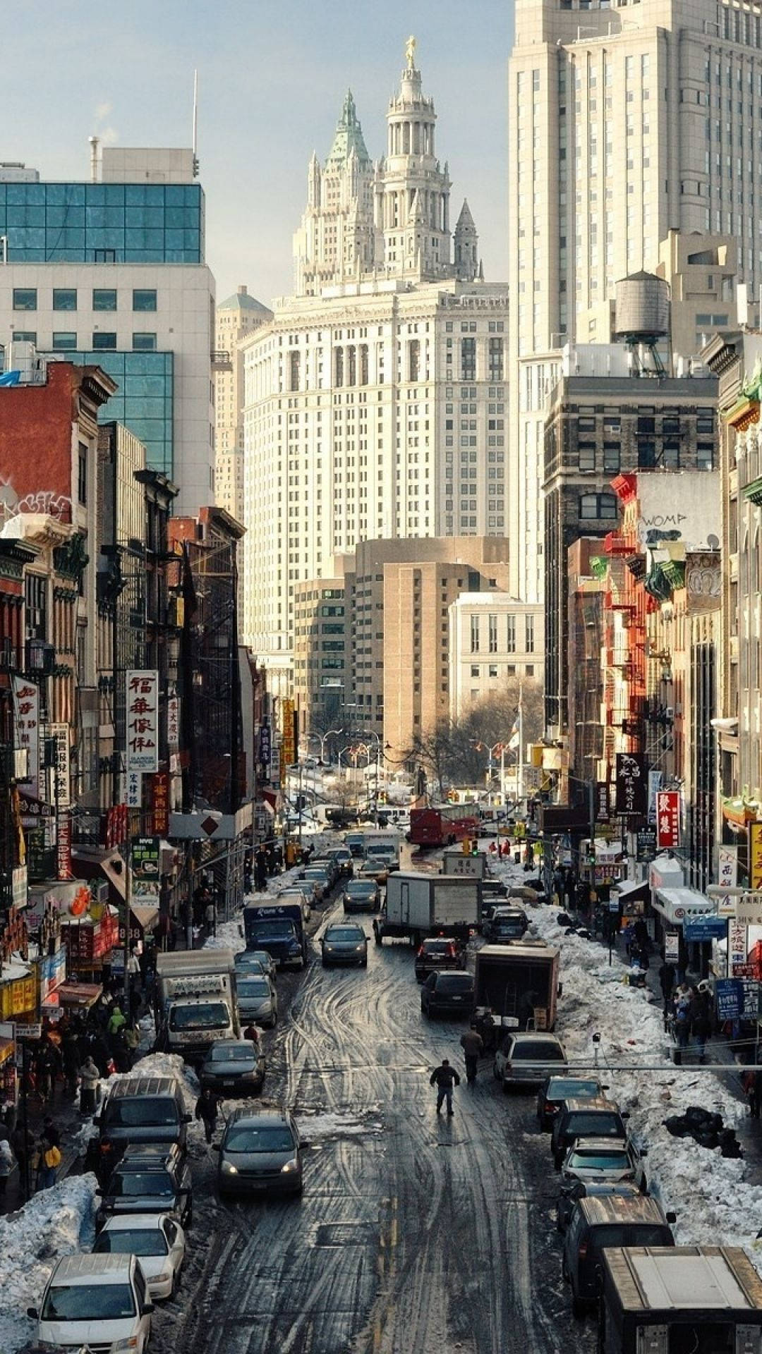 New 桌布 壁紙 — 唐人街的雪景城市街道，高樓大廈、交通和行人，天空晴朗。
