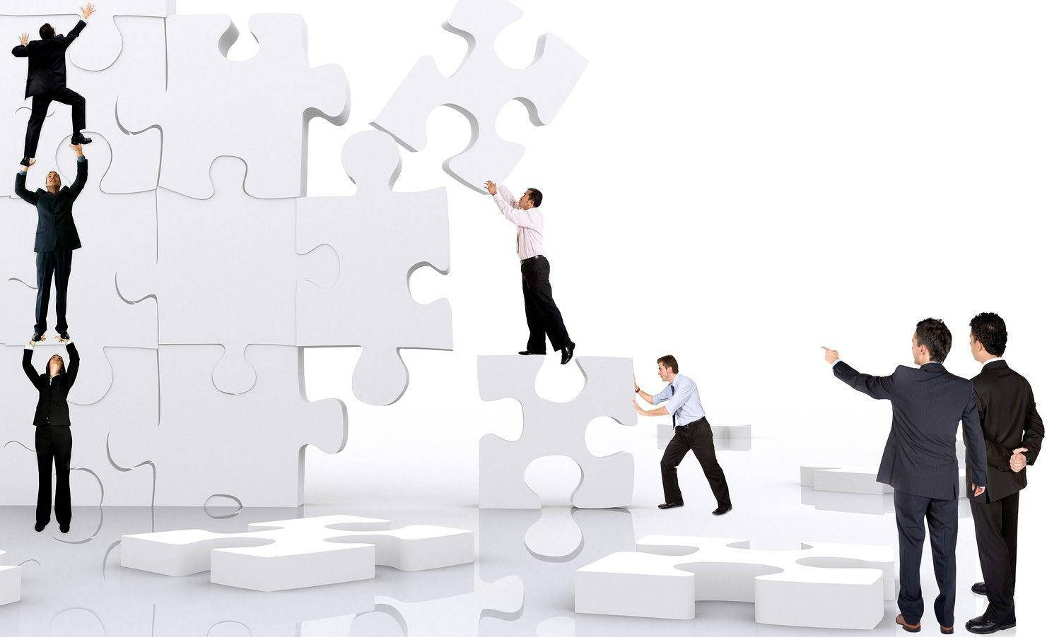 Teamwork 桌布 壁紙 — 商人攀爬並組裝巨大的白色拼圖塊，在純白背景上構建結構。
