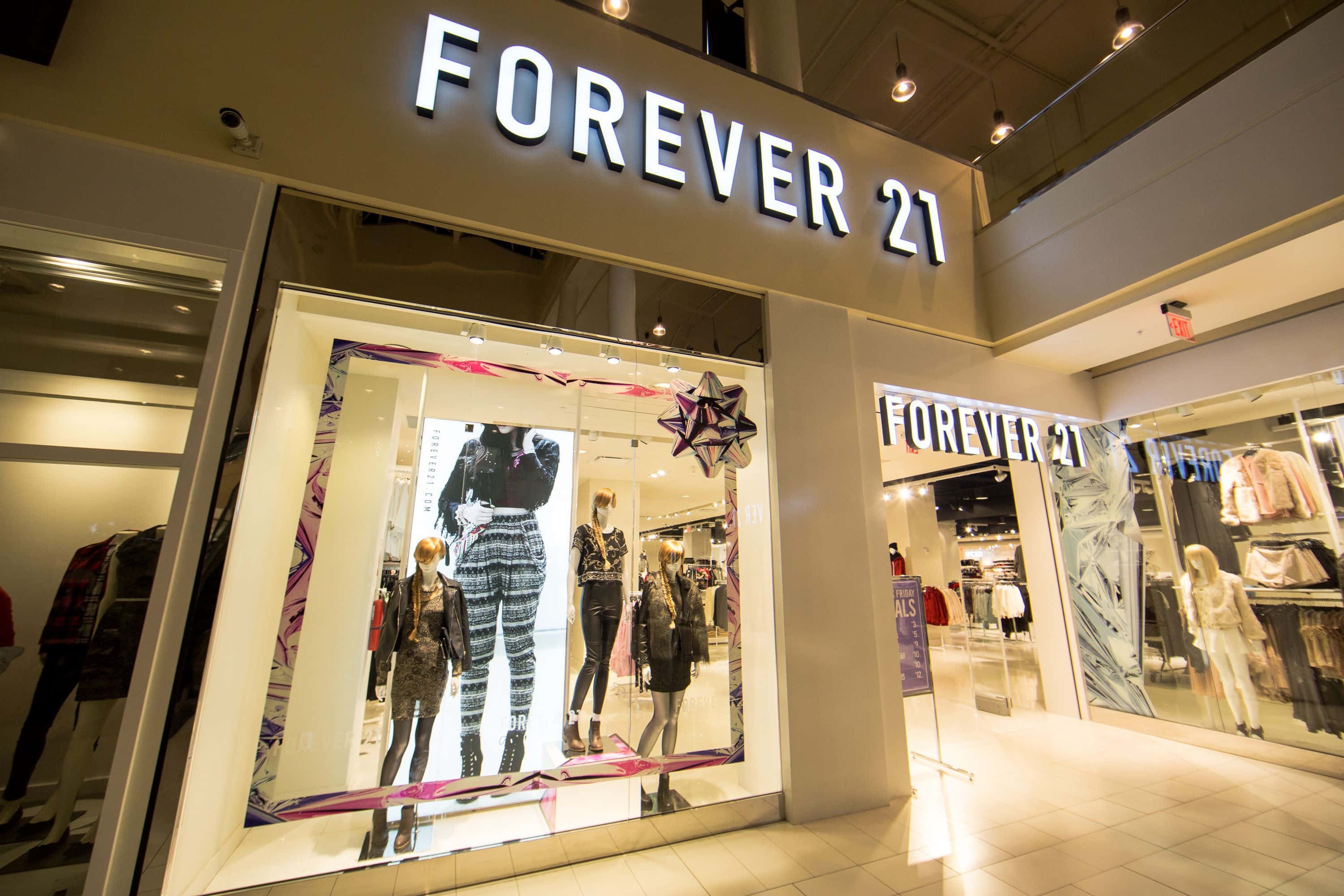 永遠21 桌布 壁紙 — 商場內Forever 21店鋪入口燈光明亮，櫥窗內展示穿著時尚服裝的人體模型。