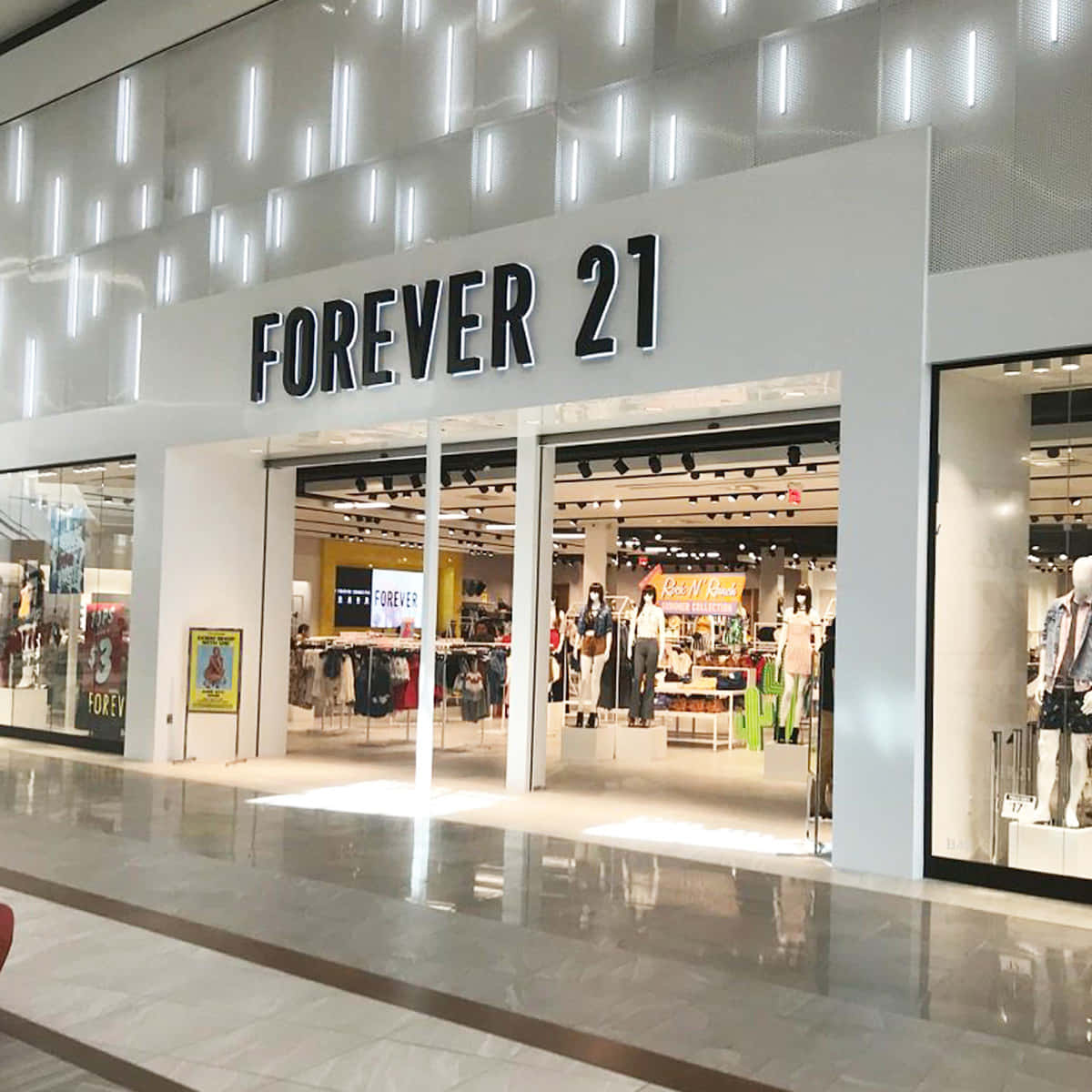 永遠21 桌布 壁紙 — 商場內明亮的Forever 21店鋪入口，設有玻璃門和展示色彩繽紛服裝的人體模型，採用現代照明。