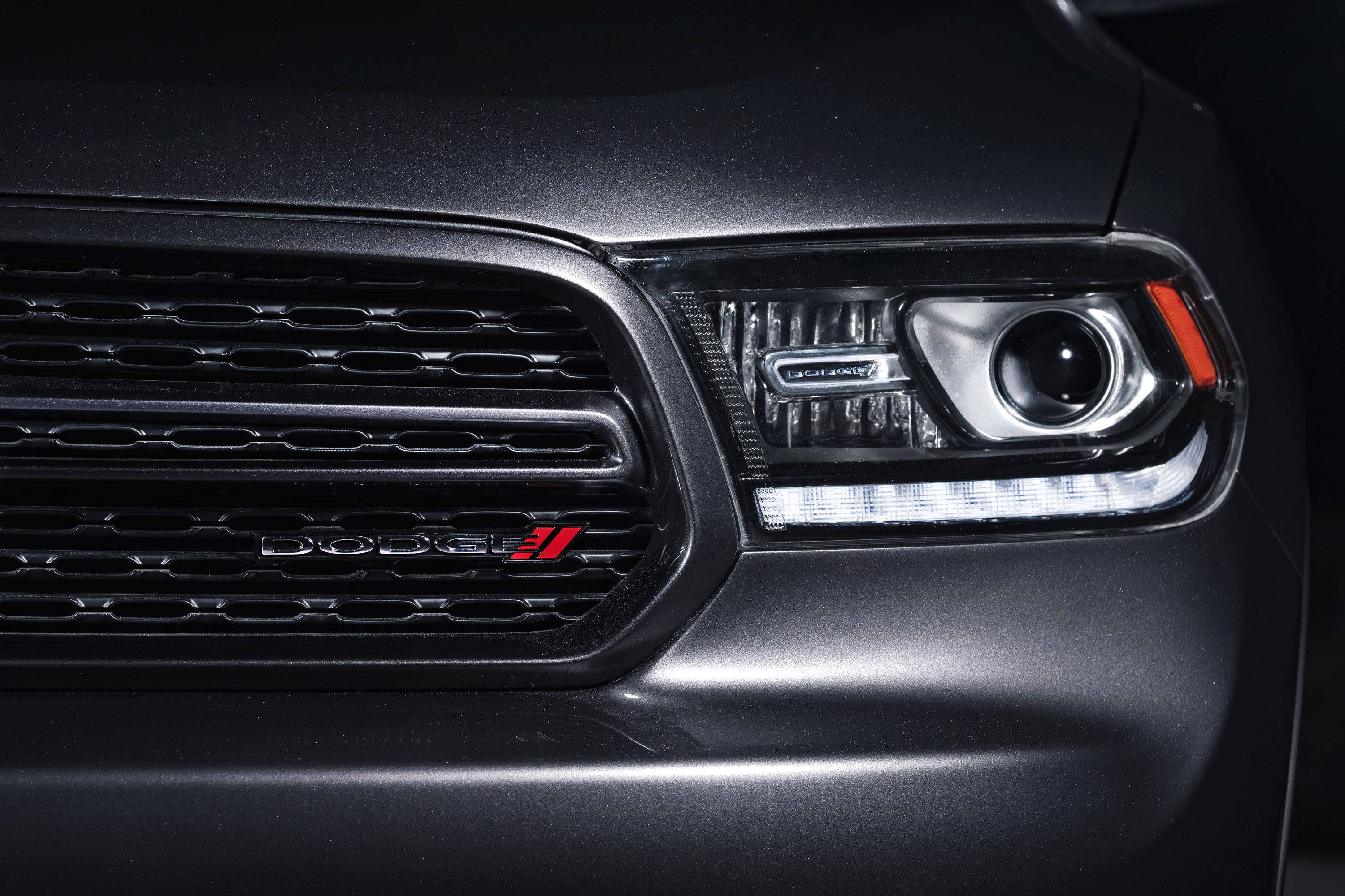 Dodge 桌布 壁紙 — 啞光黑色 Dodge 車輛前格柵和頭燈的特寫，帶有紅色點綴和鍍鉻飾條。