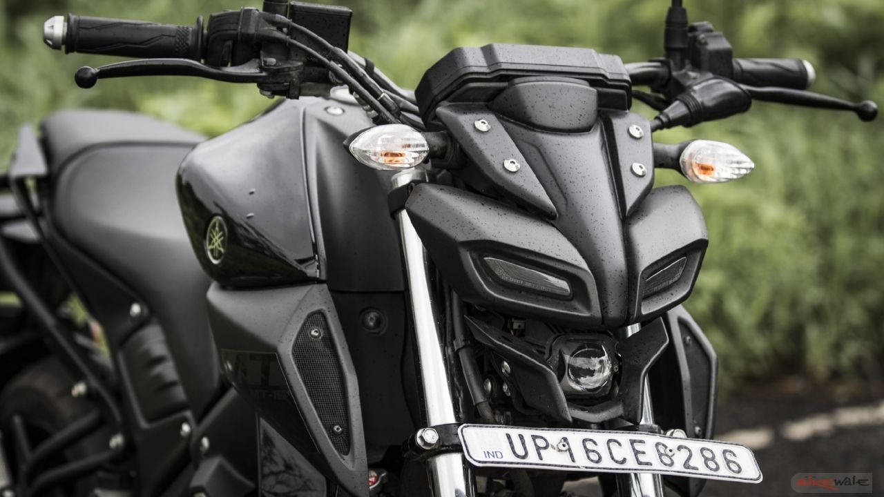 yamaha mt 15 桌布 壁紙 — 啞光黑色Yamaha摩托車的特寫，雨滴落在其流線型的前整流罩和把手。