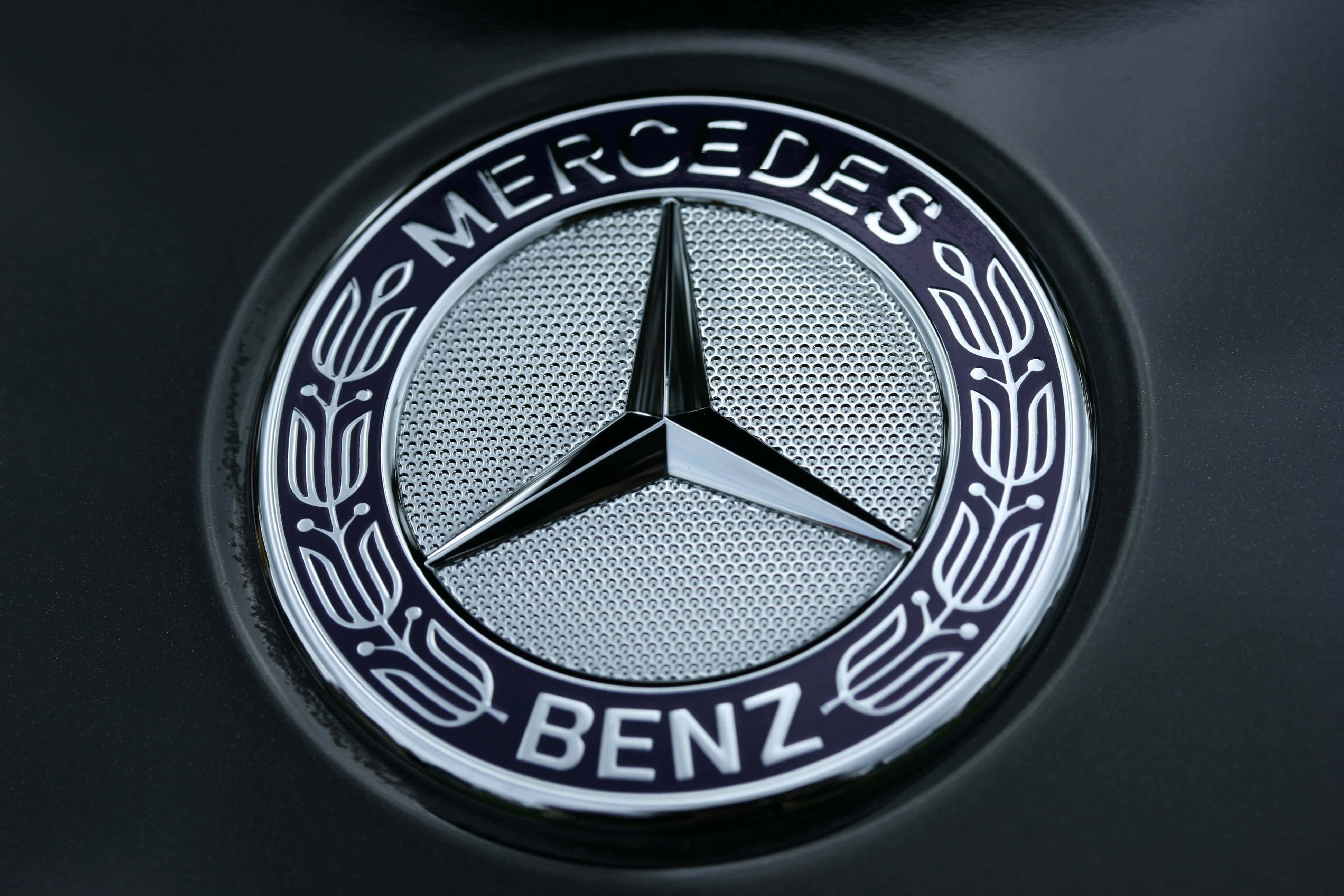 Car Logo 桌布 壁紙 — 啞光黑色汽車引擎蓋上閃閃發光的賓士標誌特寫，細節精緻。