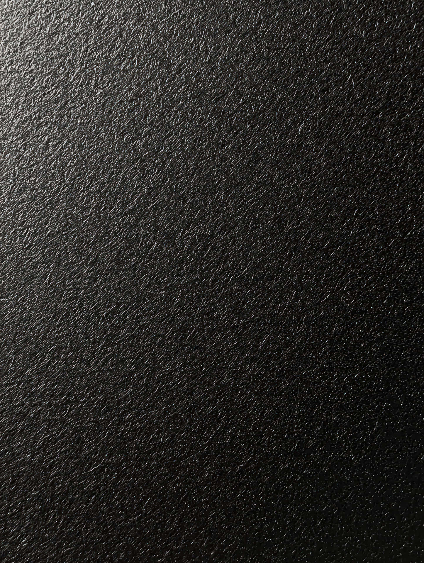 Minimalist uniform black paper texture 壁紙 — 啞光黑色紋理表面的特寫，帶有細微顆粒和柔和光線反射。