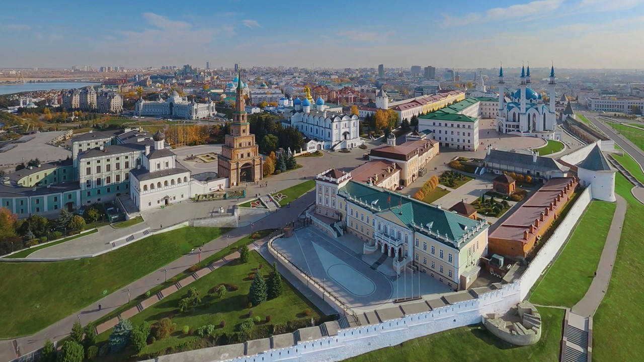 Kazan 桌布 壁紙 — 喀山克里姆林宮的鳥瞰圖，歷史悠久的塔樓和教堂被綠色草坪和秋樹環繞，在晴朗的藍天下。