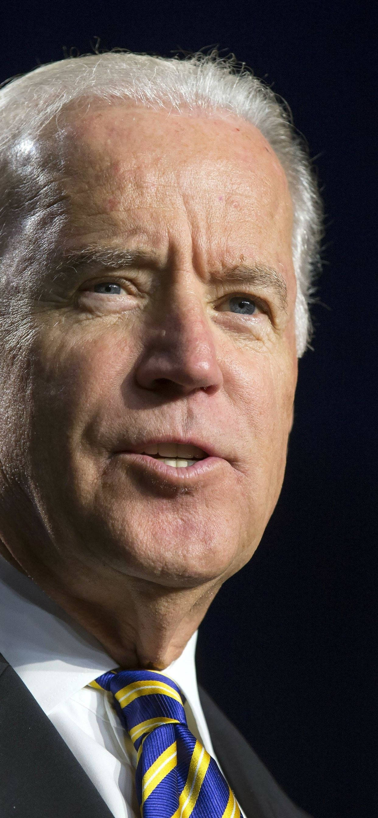 Biden 桌布 壁紙 — 喬·拜登在深色背景下說話的嚴肅表情特寫肖像。
