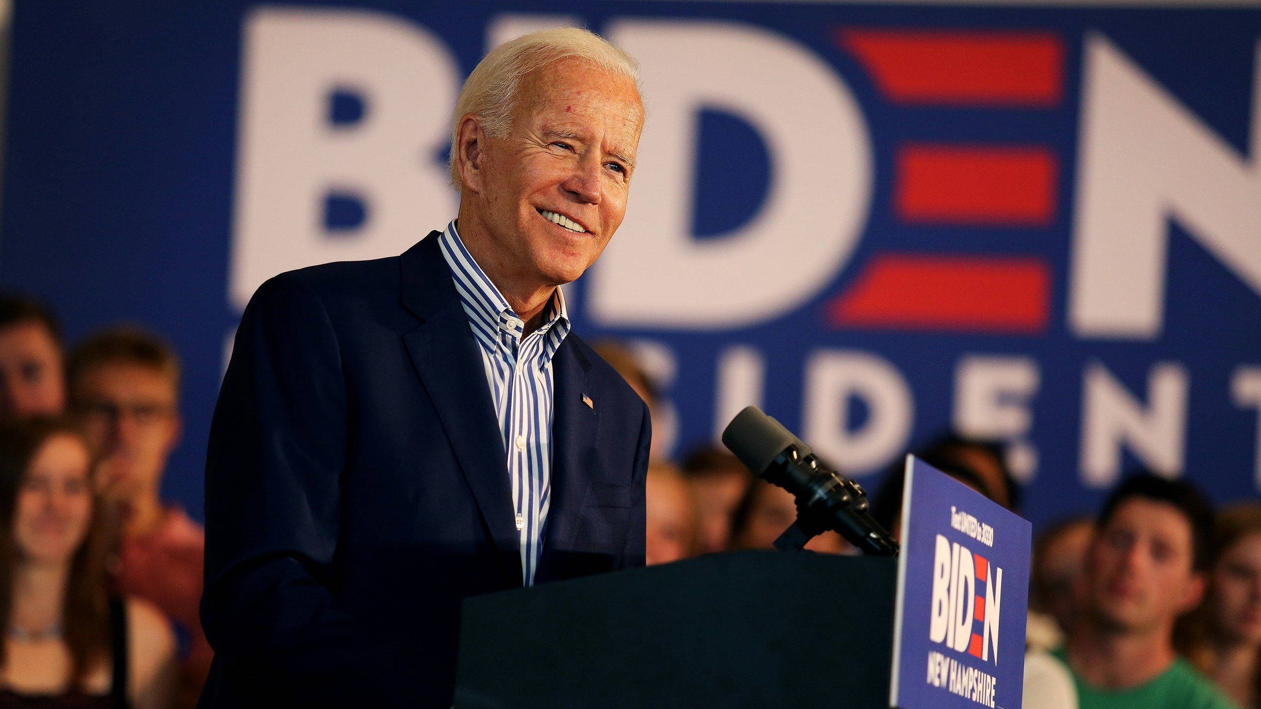 Biden 桌布 壁紙 — 喬·拜登在競選集會上溫暖微笑，背景為「BIDEN PRESIDENT」及身後人群。