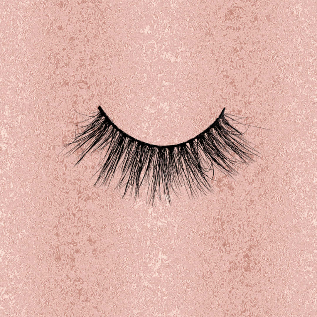 Eyelash 桌布 壁紙 — 單根黑色假睫毛在柔軟質感的腮紅粉紅背景上優雅地彎曲。
