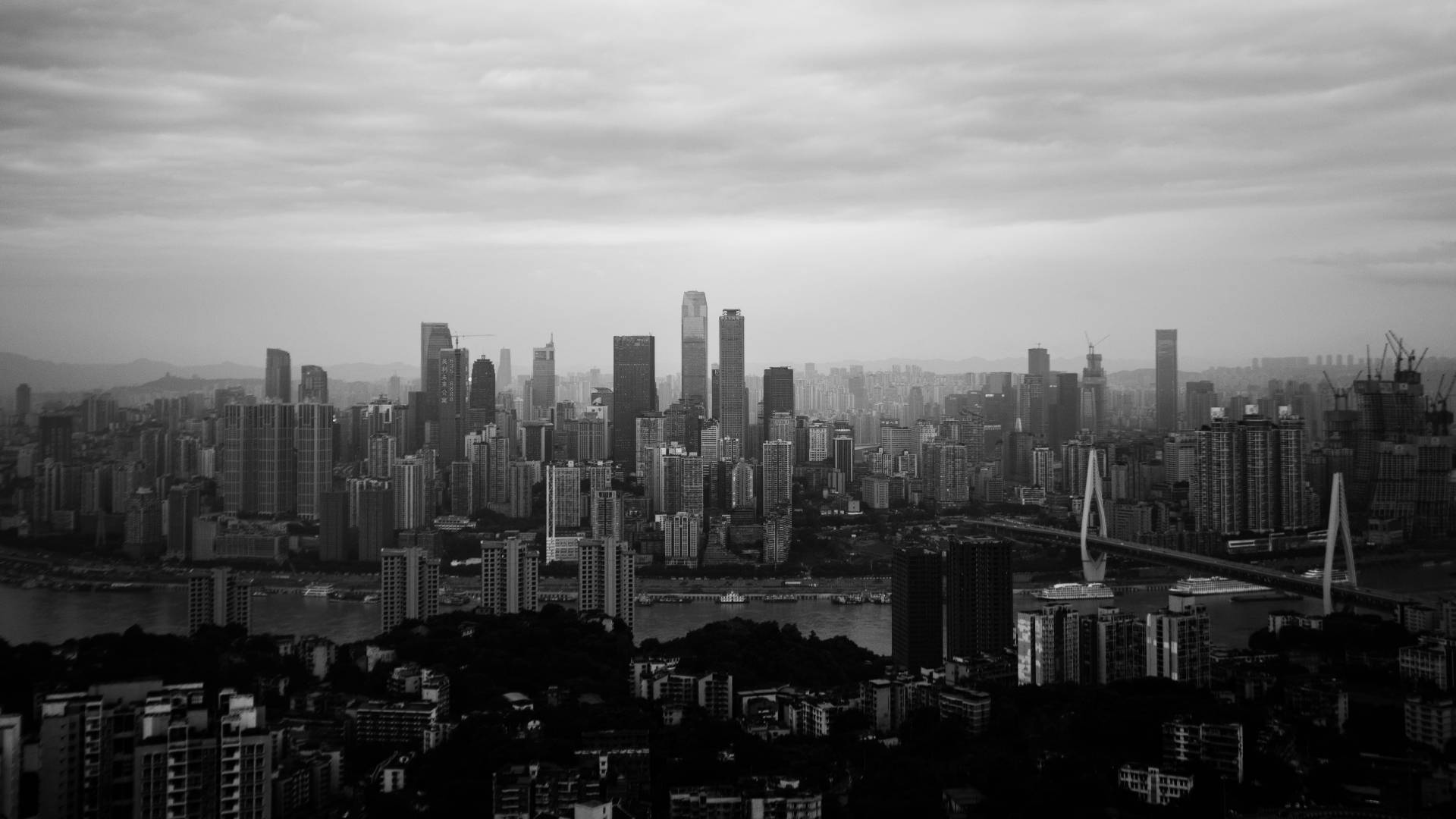 Chongqing 桌布 壁紙 — 單色城市景觀，高聳的摩天大樓和河橋在陰天之下。