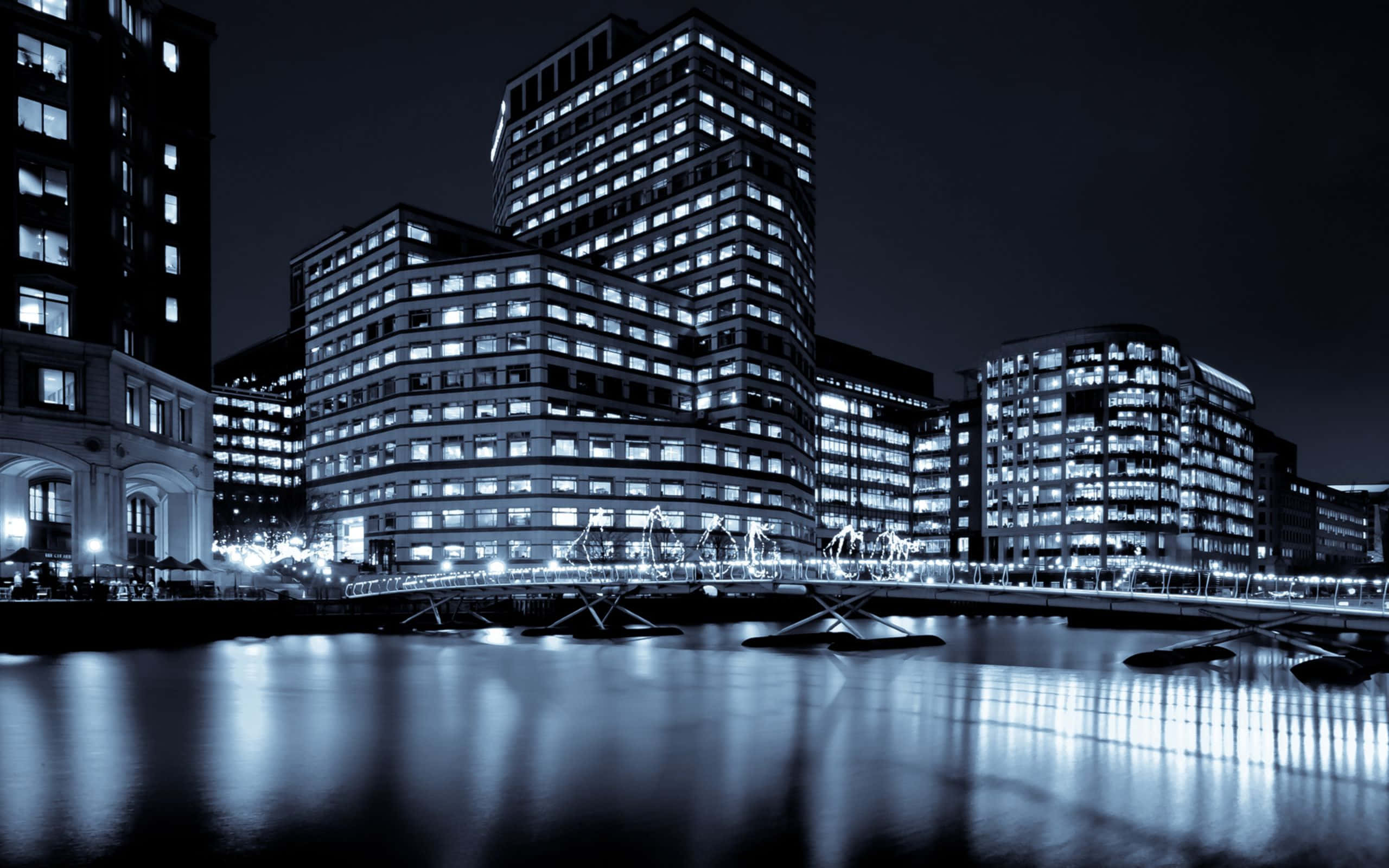 Black And White Cityscape 桌布 壁紙 — 單色夜景城市景觀，現代建築燈光在平靜水面上倒映，天空漆黑。