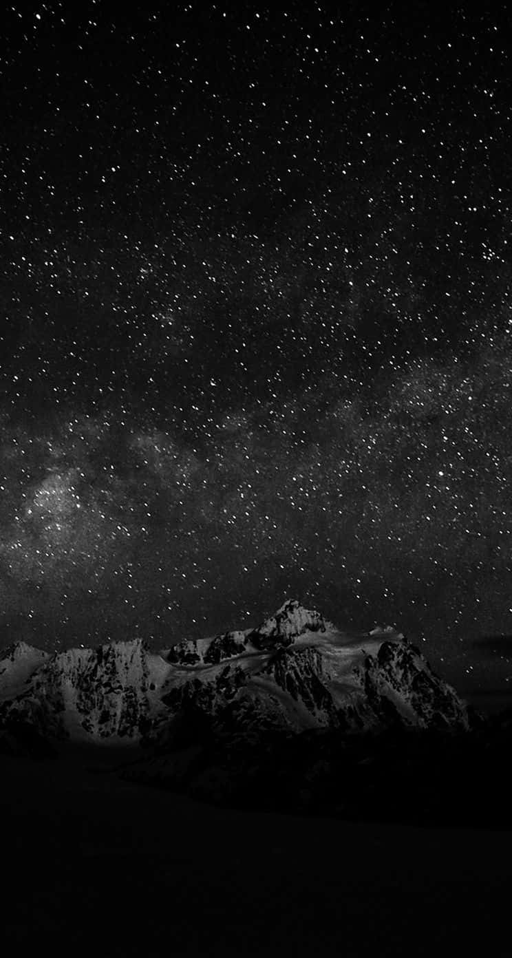 Dark Sky 桌布 壁紙 — 單色夜空佈滿無數星星，銀河在積雪山脈上空拱起。