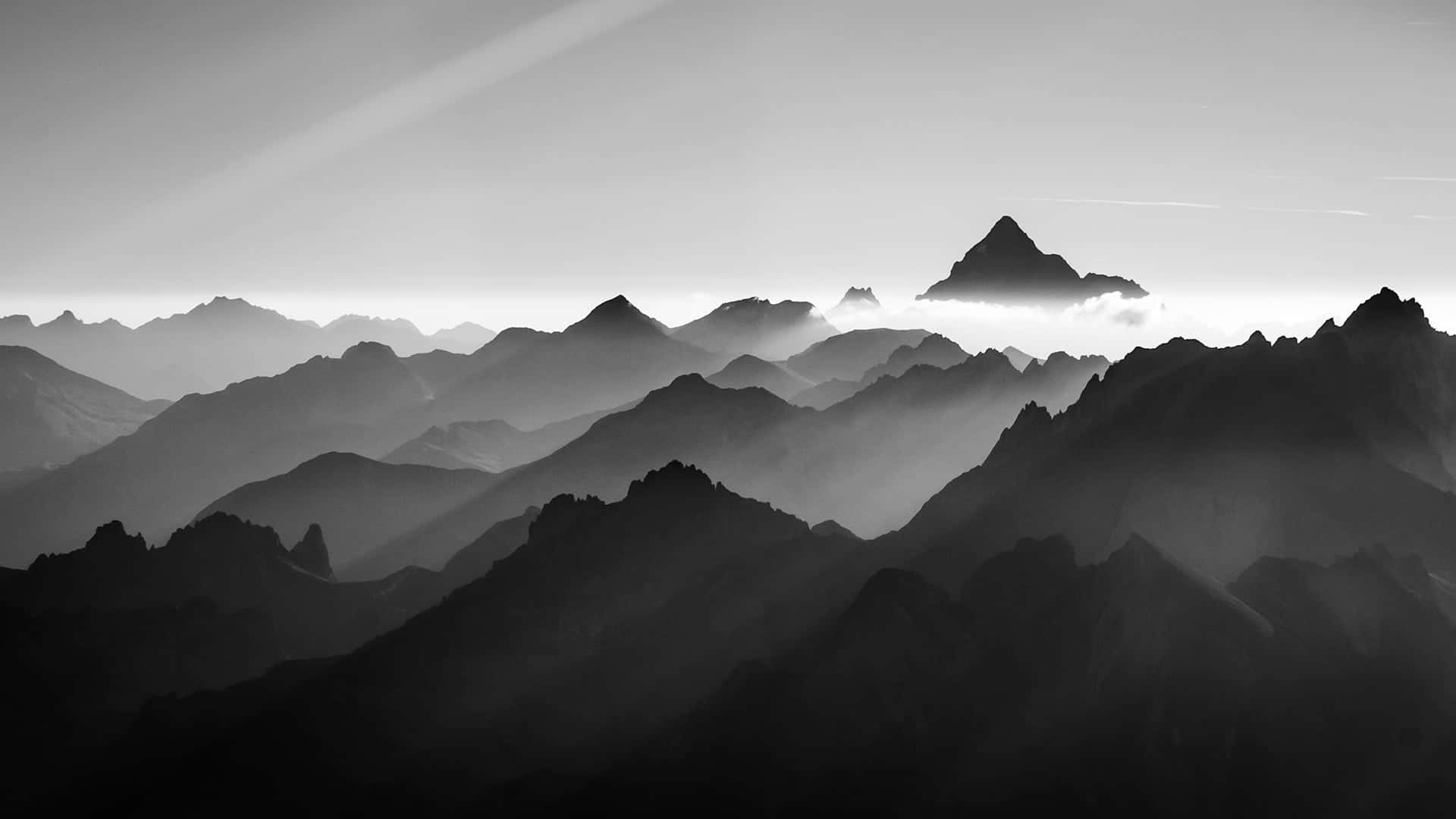Minimalist Monochrome 桌布 壁紙 — 單色山脈層次逐漸融入霧中，柔和的光束穿透大氣薄霧。