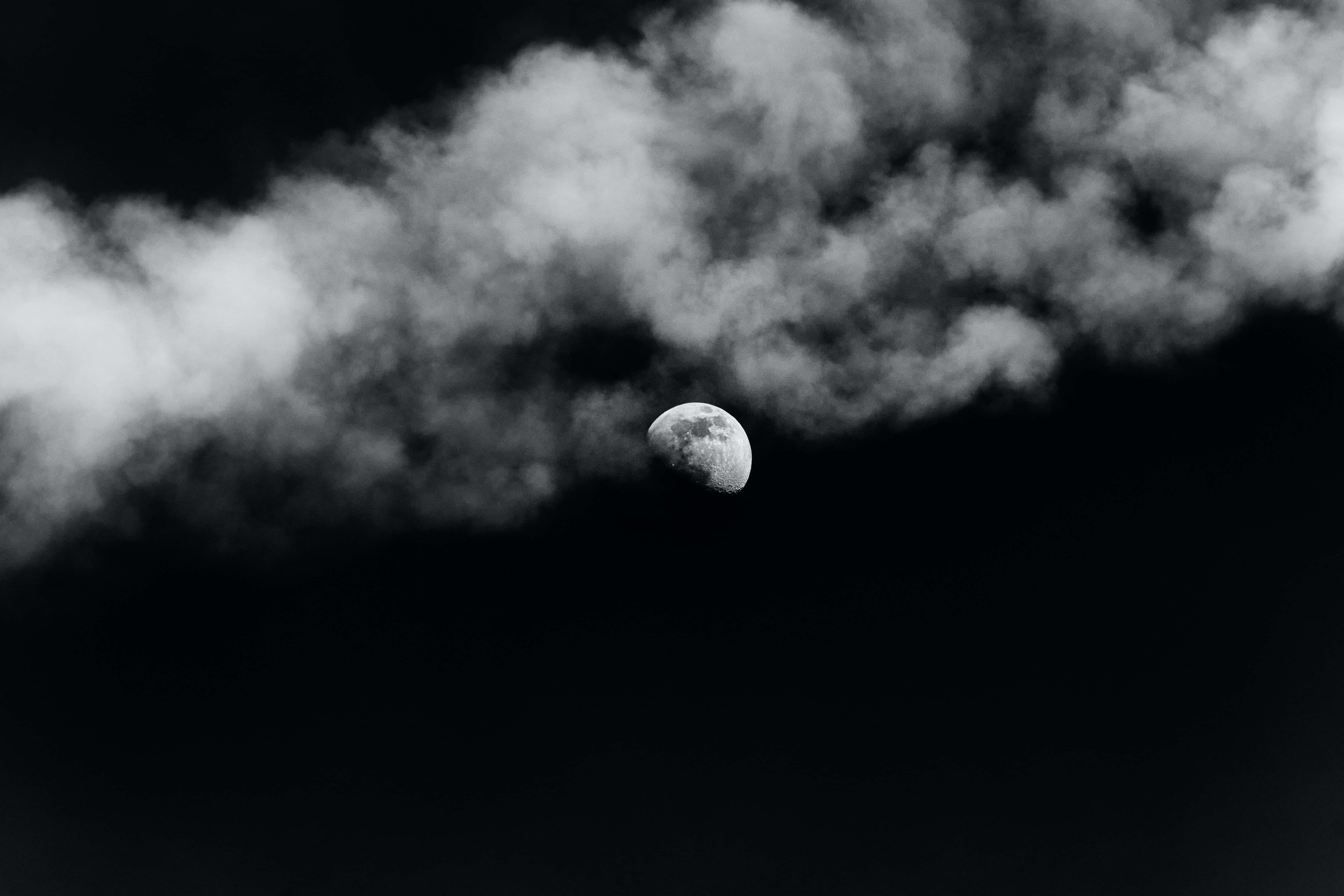 Dark Moon 桌布 壁紙 — 單色新月穿過縷縷雲層，在深邃的黑色夜空中若隱若現。