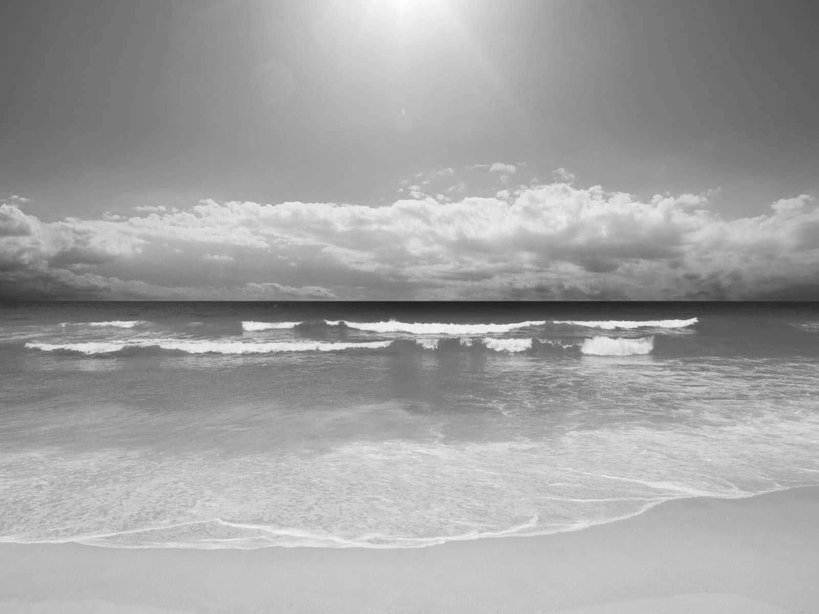 Black And White Beach 桌布 壁紙 — 單色海灘場景，在戲劇性的多雲天空下，溫柔的海浪拍打著沙灘。