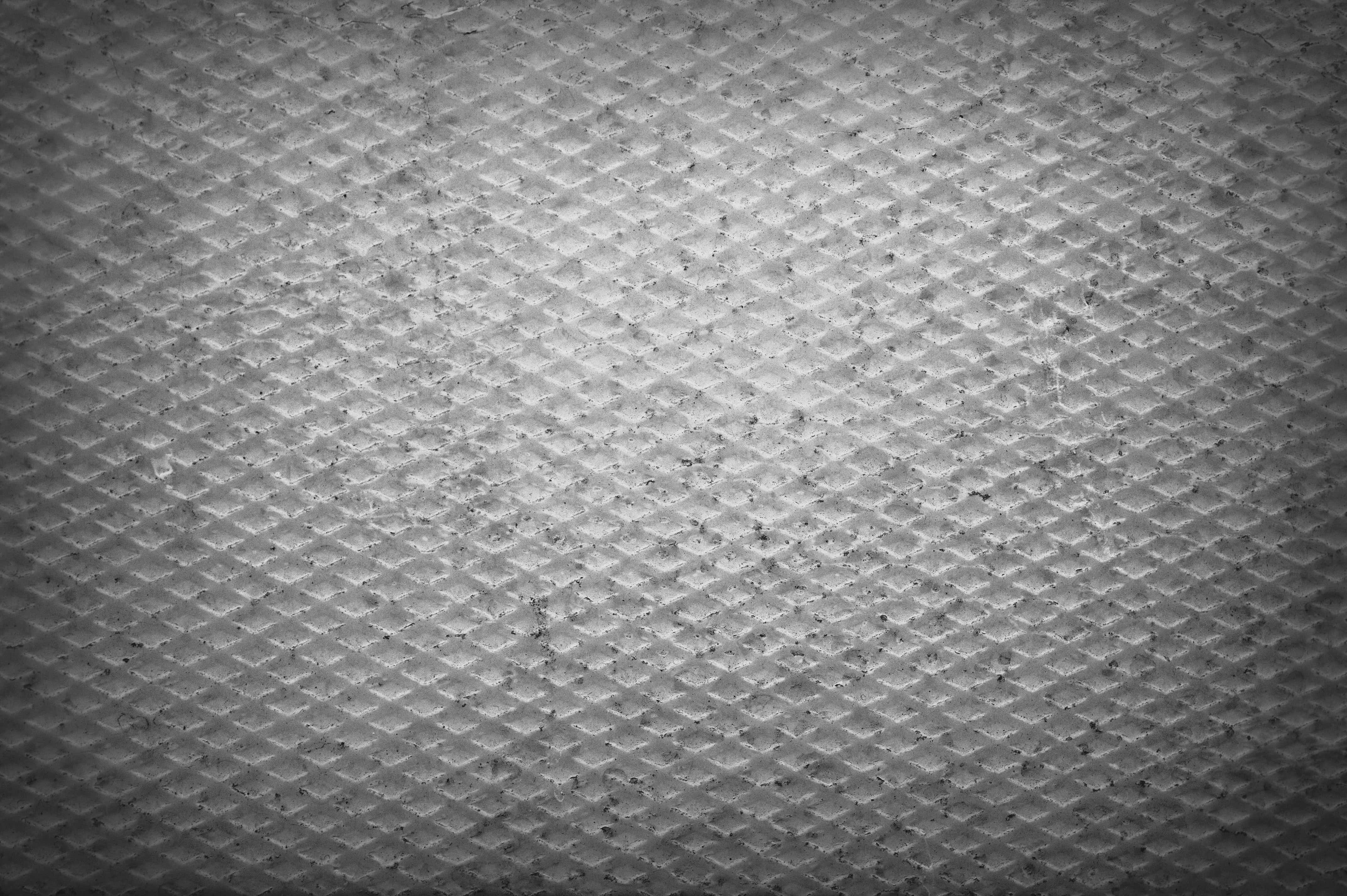 Gray Texture 桌布 壁紙 — 單色特寫，呈現帶有紋理的鑽石圖案表面，具有微妙的磨損和暗角照明。