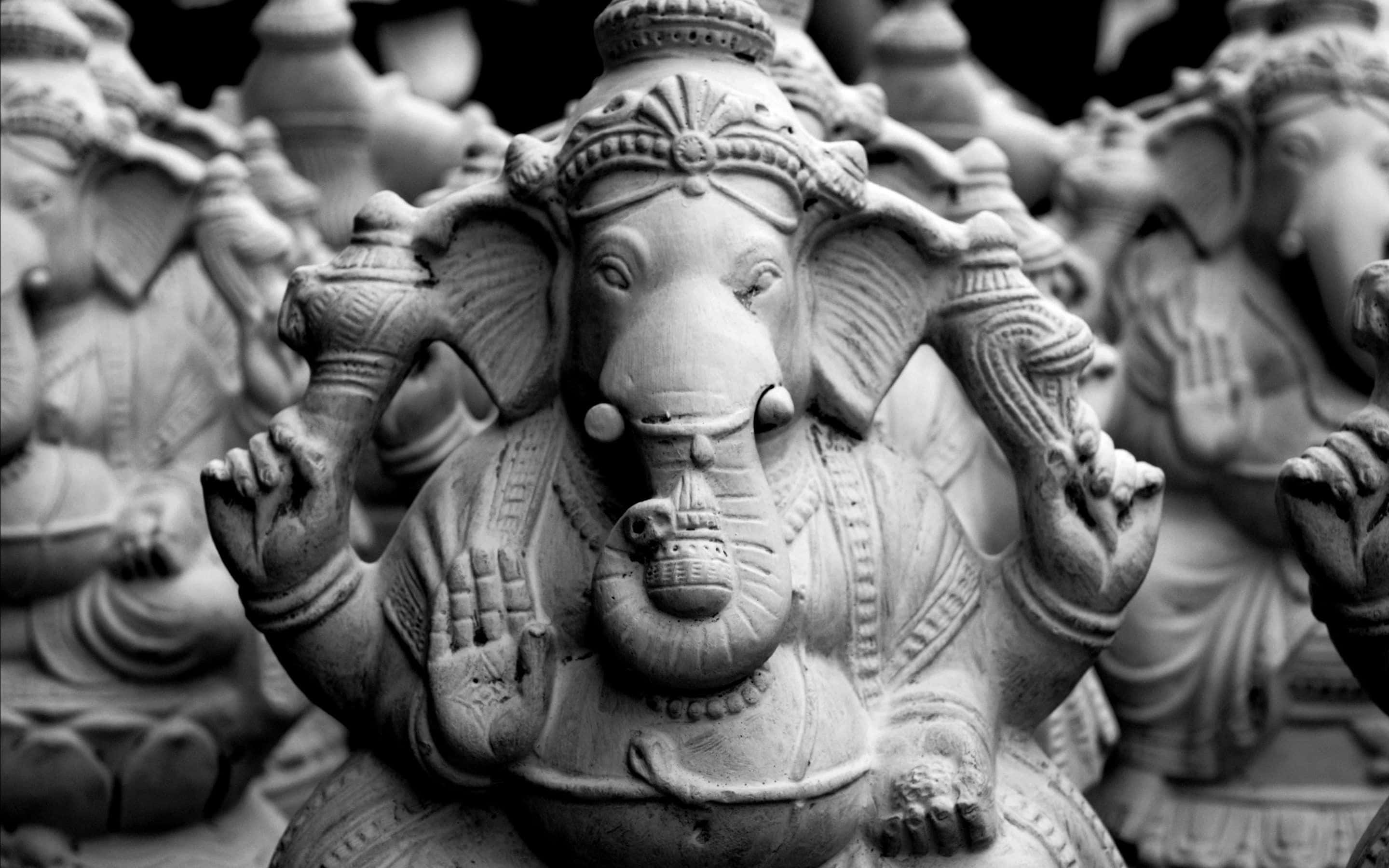 Ganesh 桌布 壁紙 — 單色特寫，細節豐富的象頭神像，周圍環繞著相同的雕像，景深較淺。