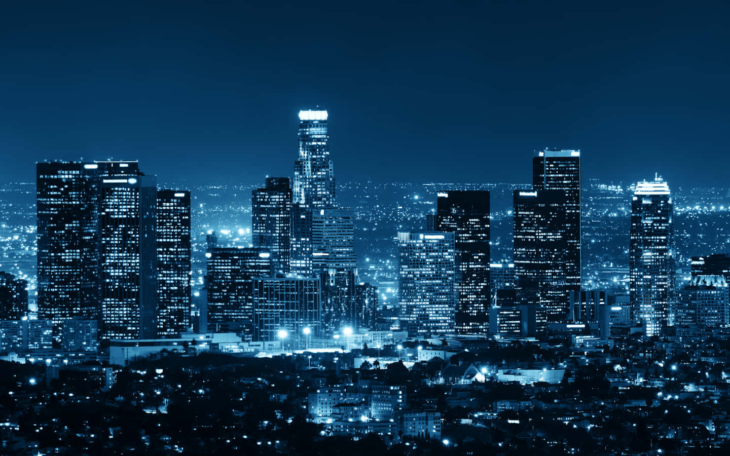 La 桌布 壁紙 — 單色藍調的夜間城市景觀，高聳的摩天大樓在黑暗的天空中閃耀。