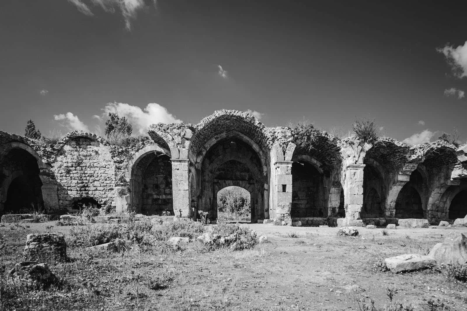 Middle Ages 桌布 壁紙 — 單色調的古代石拱門遺跡在散佈著雲朵的戲劇性天空下莊嚴地矗立。