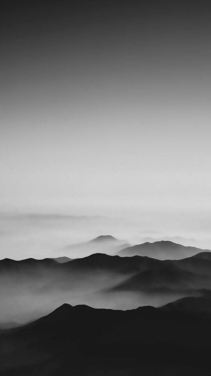 Black And White iPhone 桌布 壁紙 — 單色霧山在平靜的天空下逐漸融入柔和的灰色漸變。
