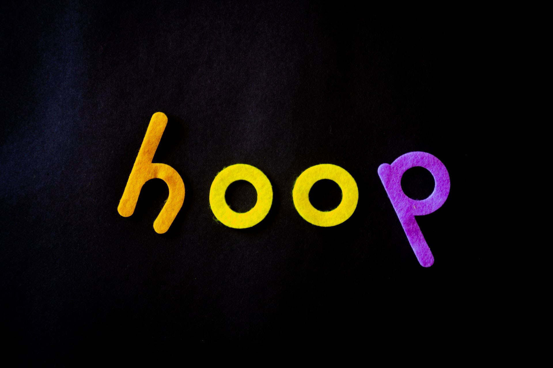 Facebook 封面 桌布 壁紙 — 單詞 'hoop' 用彩色氈布字母拼寫在深色紋理背景上。