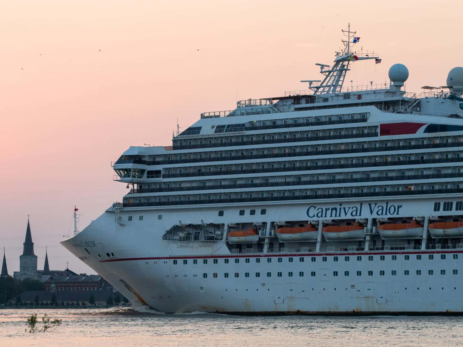 Carnival Dream 桌布 壁紙 — 嘉年華勇氣號郵輪在日落時分滑過平靜的水面，背景中可見歷史悠久的尖塔。