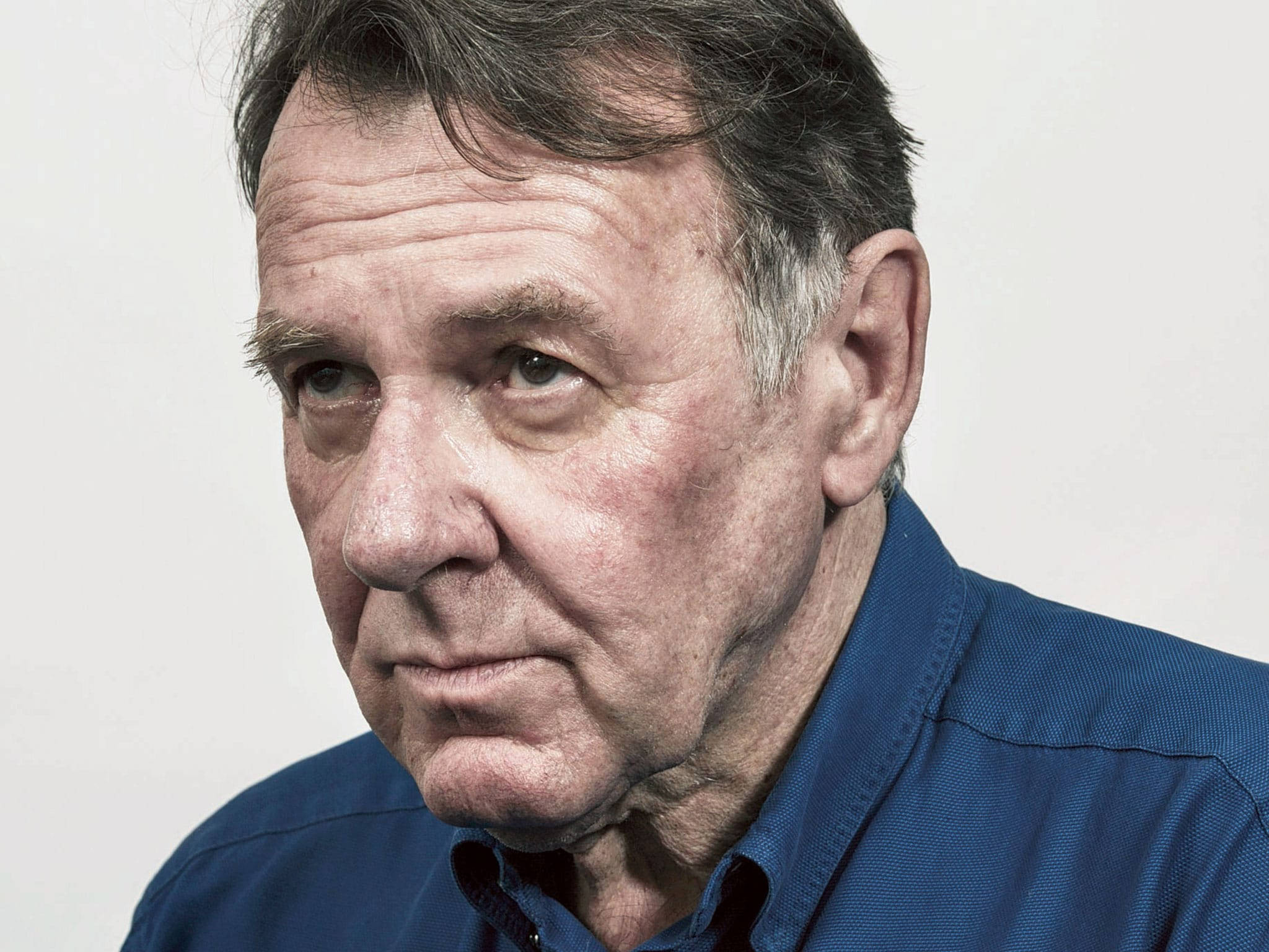 actor 桌布 壁紙 — 嚴肅中年男子特寫肖像，深皺紋，身穿藍色襯衫，背景為純白色。