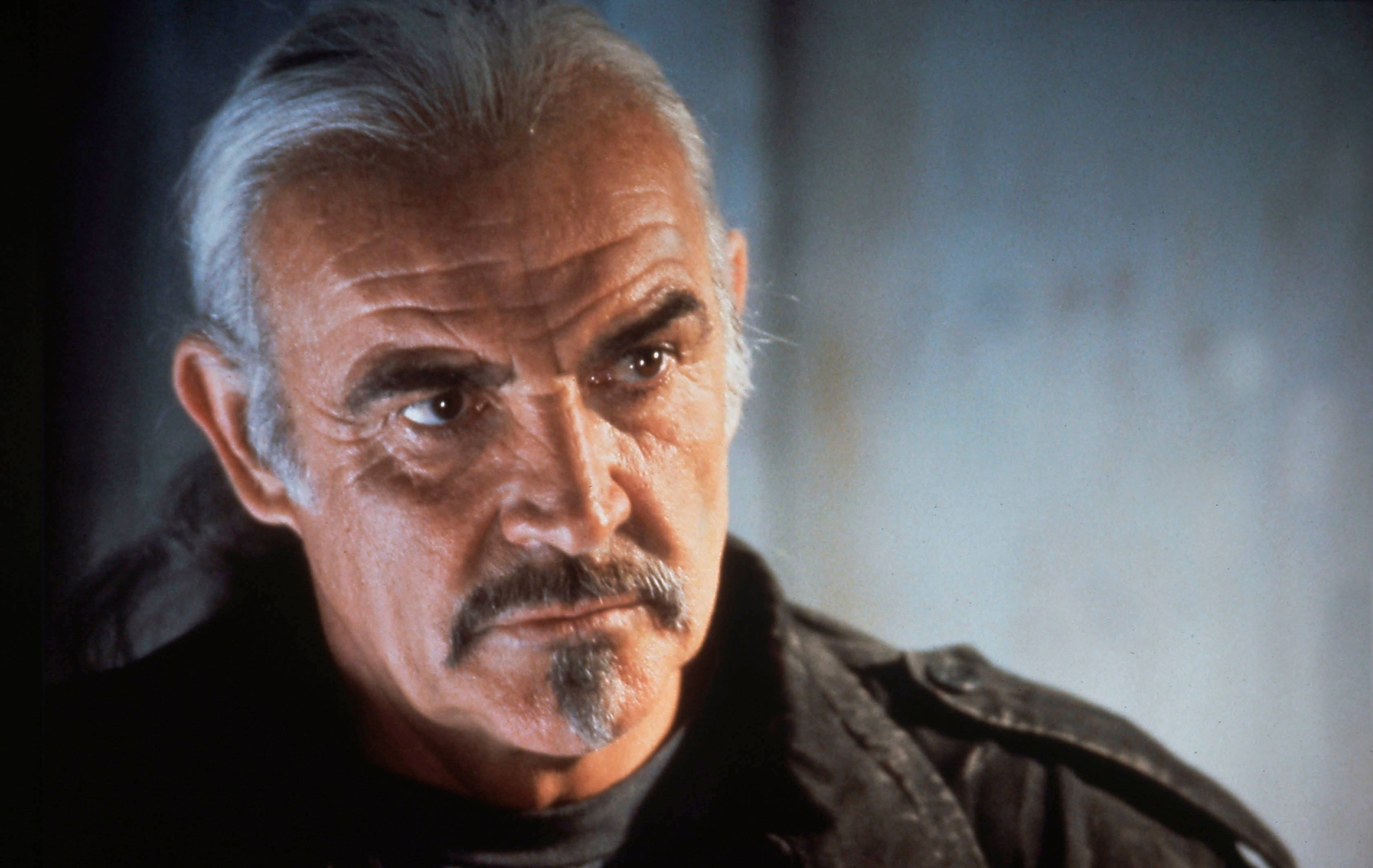 Sean Connery 桌布 壁紙 — 嚴肅年長男士的近距離特寫，灰白頭髮和鬍鬚，在昏暗燈光下凝視鏡頭。