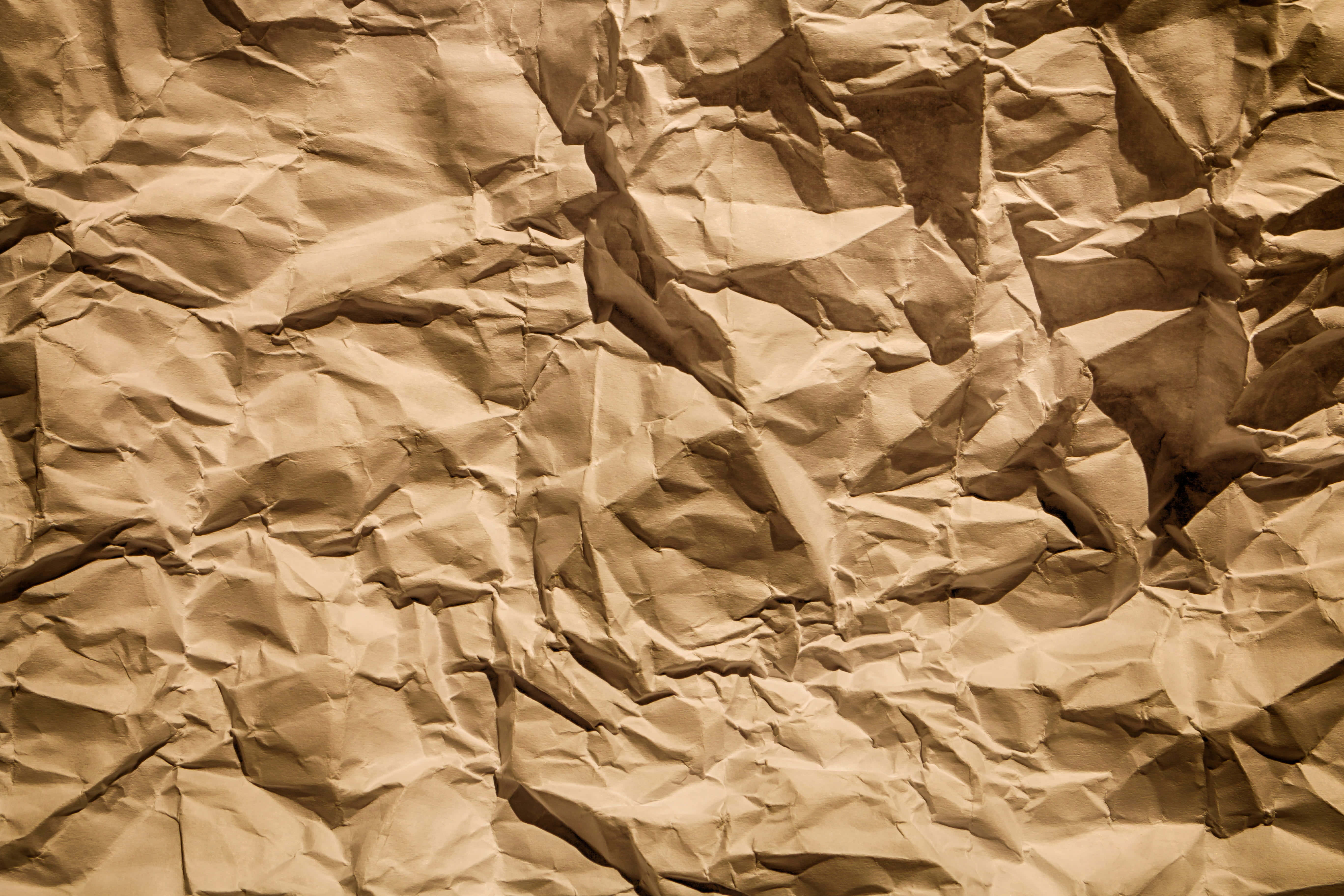 Brown Paper 桌布 壁紙 — 嚴重皺摺的棕色紙張特寫，帶有深摺痕和溫暖的懷舊色調，營造出觸感紋理表面。