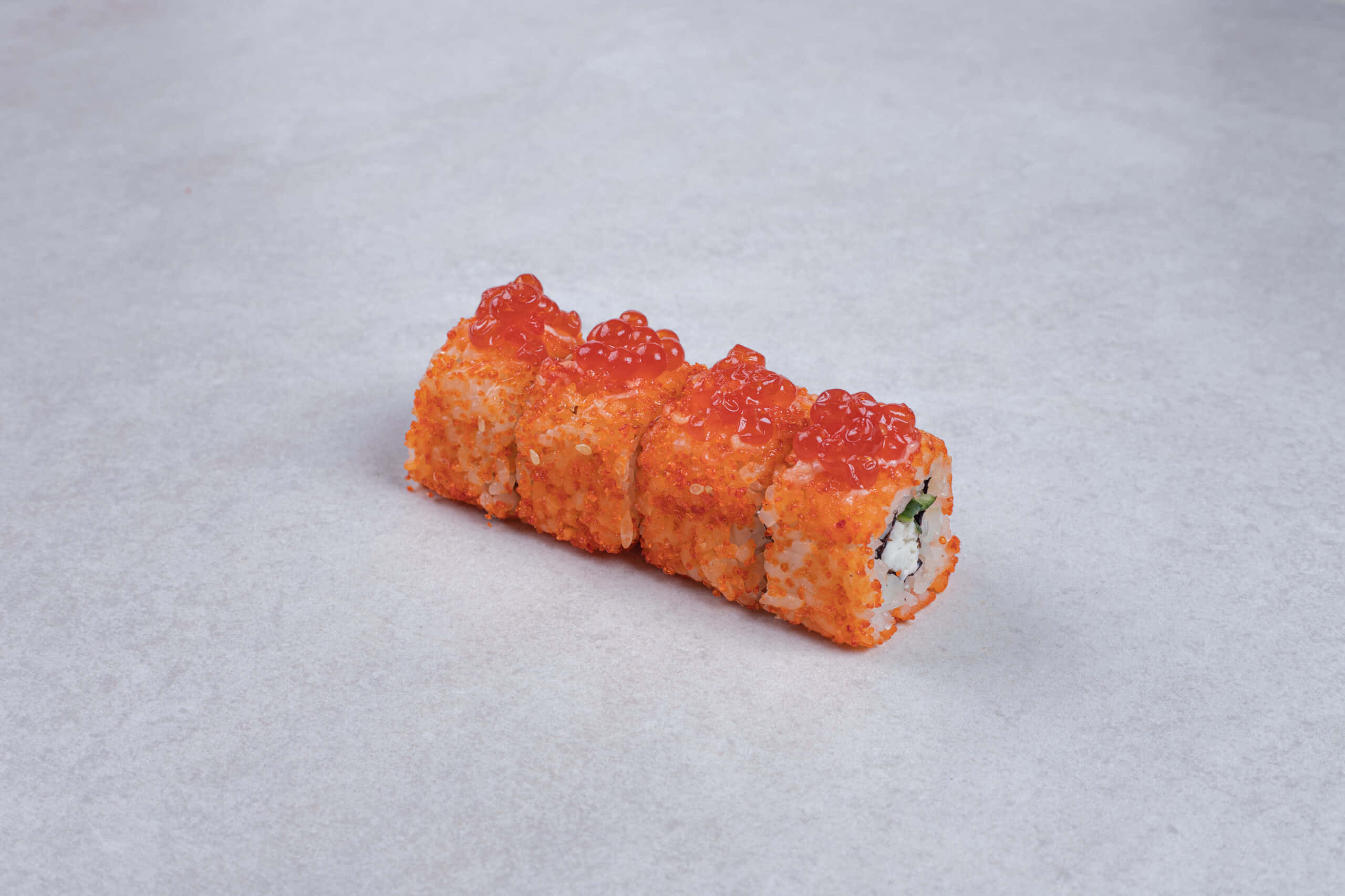 Sushi 桌布 壁紙 — 四件壽司卷上面鋪滿鮮橙色飛魚籽和酥脆天婦羅碎，放在有紋理的灰色表面上。