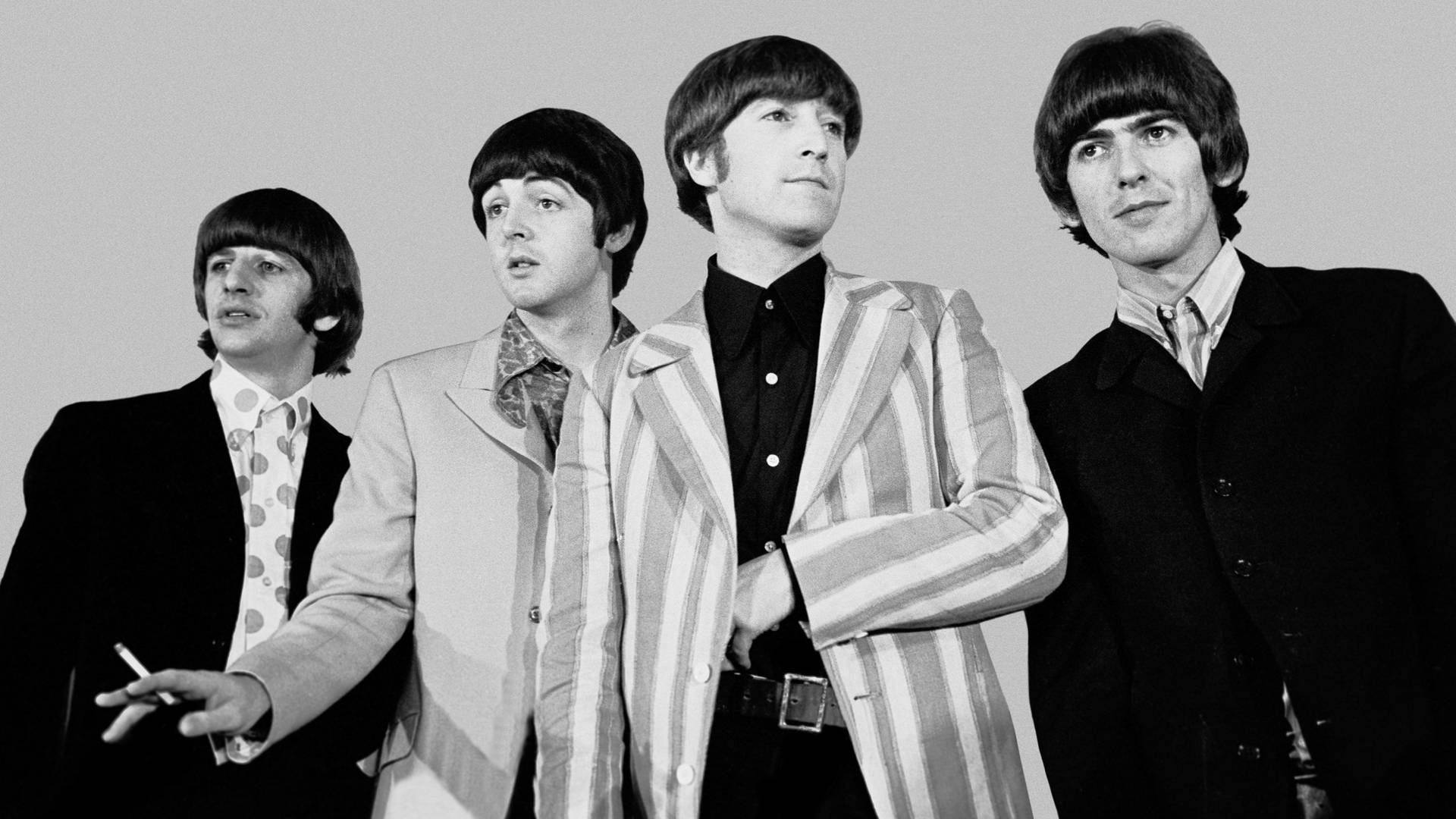 Beatles 桌布 壁紙 — 四位1960年代標誌性音樂家身穿時尚西裝，在純色背景前擺姿勢，散發出酷炫自信和復古魅力。
