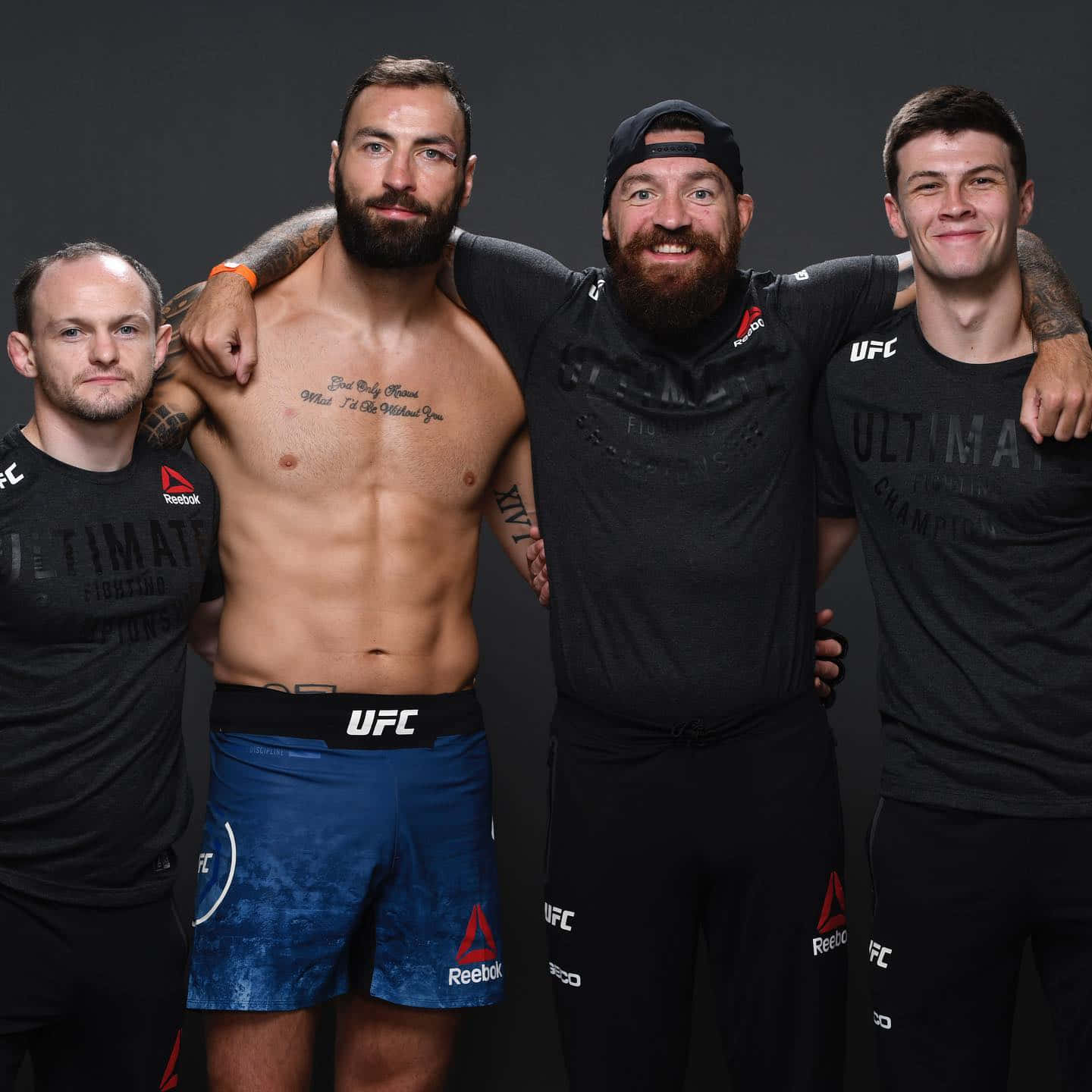 UFC 桌布 壁紙 — 四位UFC拳手在深色背景的攝影棚中自信擺姿勢，展示刺青和品牌裝備。