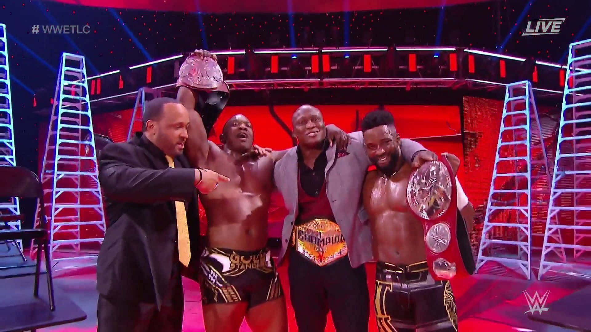 WWE 桌布 壁紙 — 四位WWE摔角手在紅色擂台舞台上，於明亮燈光下手持冠軍腰帶和梯子慶祝勝利。