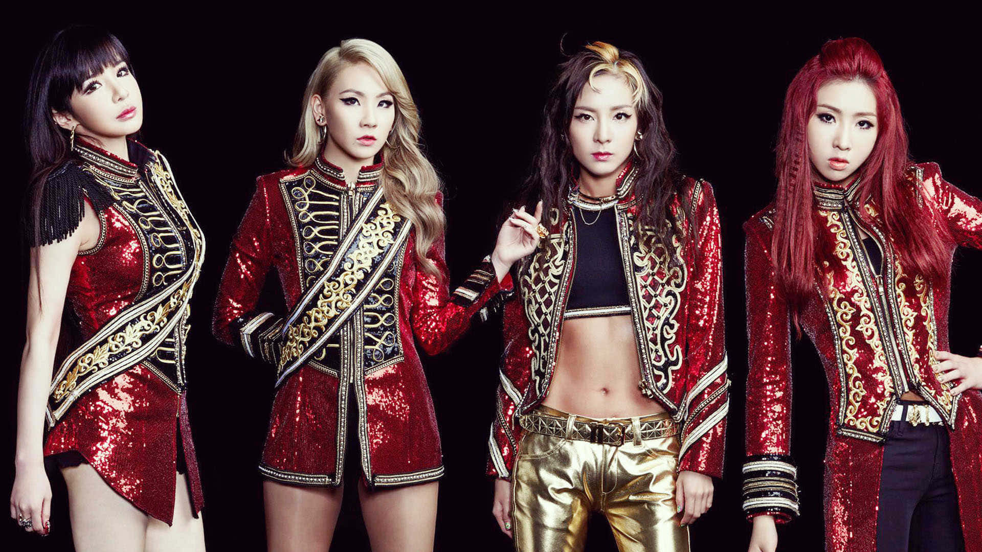 Cute Kpop 桌布 壁紙 — 四位女士身穿耀眼的紅色和金色亮片服裝，在黑色背景前自信地擺姿勢。