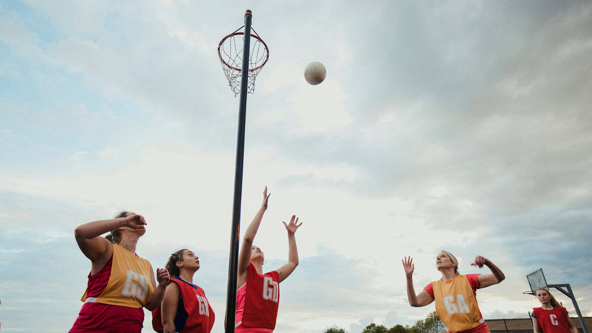 ball 桌布 壁紙 — 四位女子籃網球運動員在陰天中跳起並伸手接球。