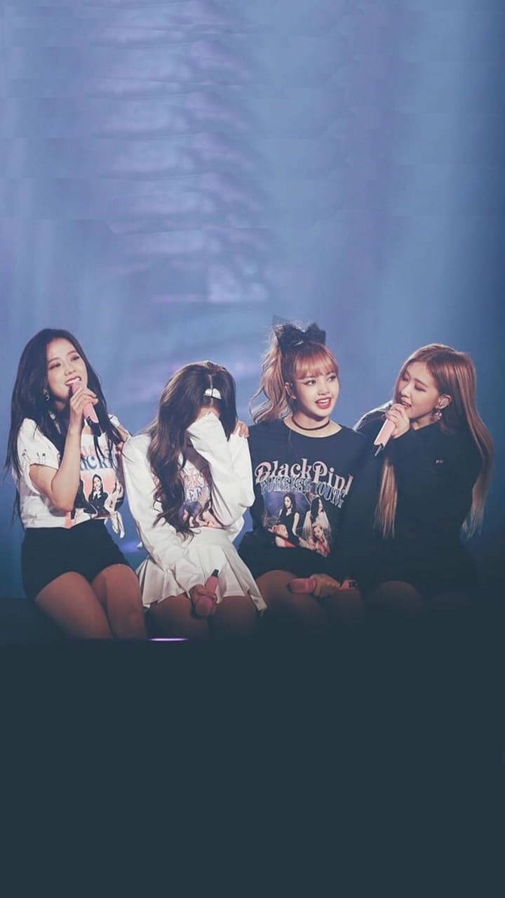 BLACKPINK 桌布 壁紙 — 四位女性K-pop偶像在藍色燈光下坐在舞台上，在演唱會表演期間手持麥克風。