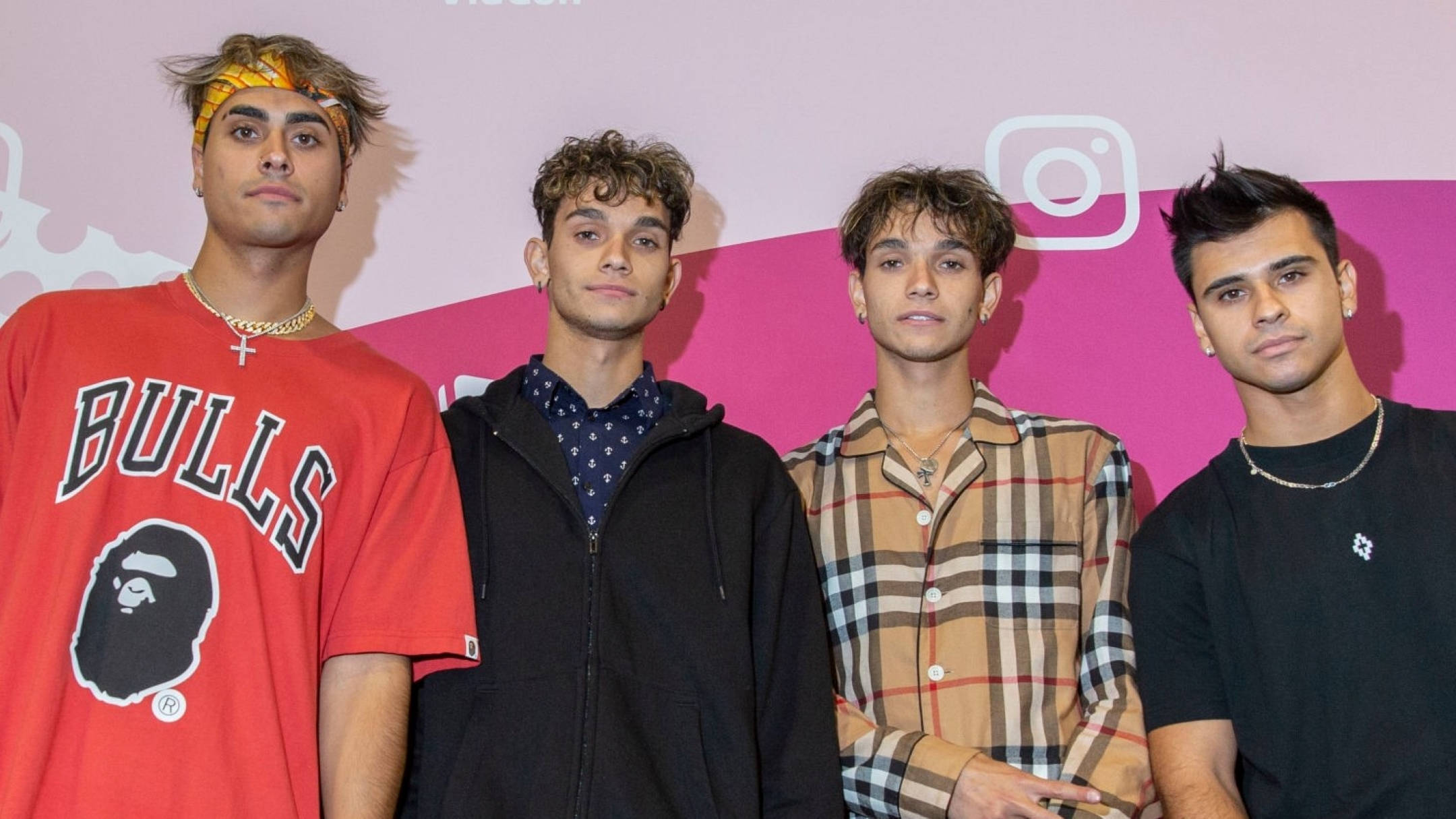 Dobre 桌布 壁紙 — 四位年輕男士身穿時尚街頭服飾，在帶有Instagram標誌的粉紅色背景前自信地擺姿勢。