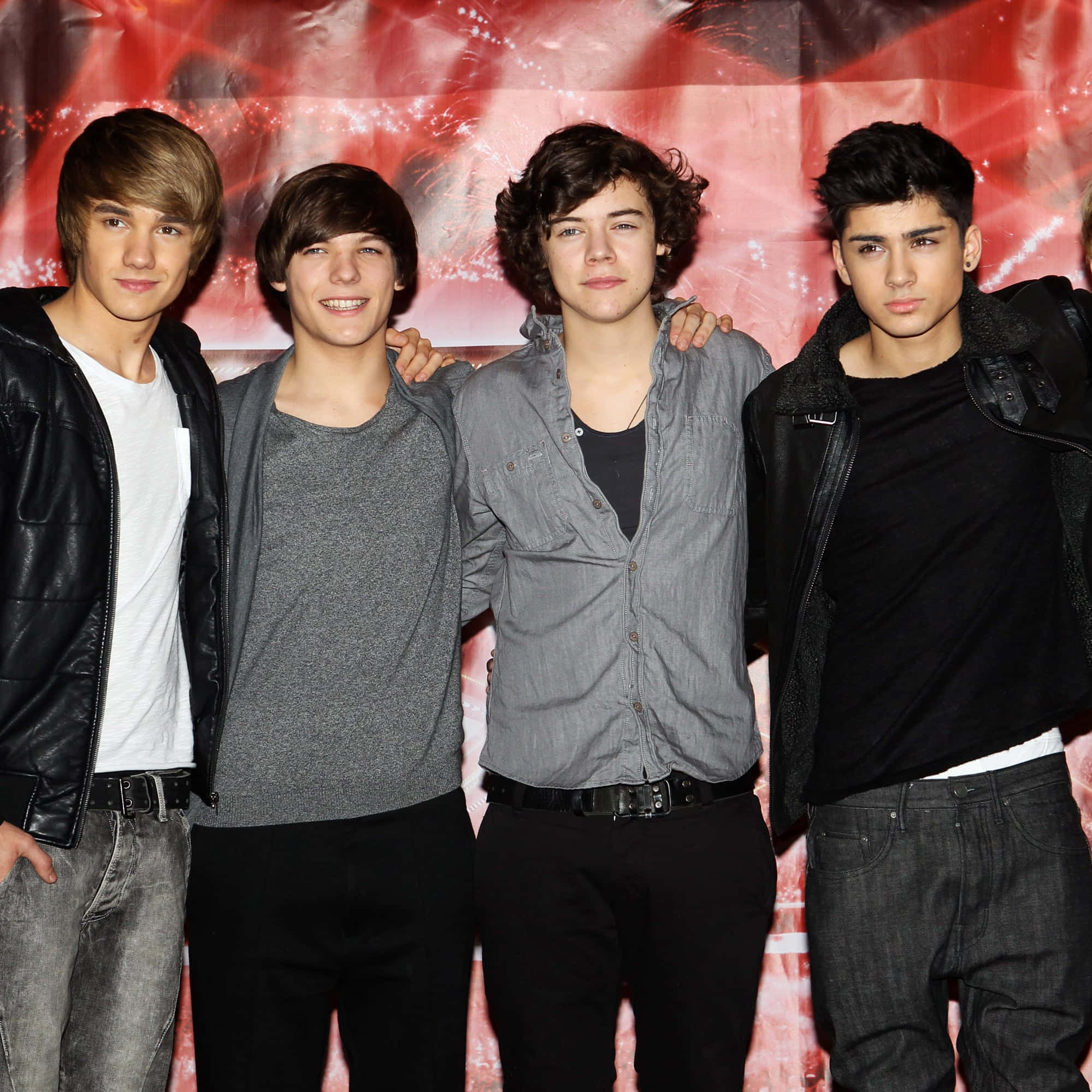 One Direction 桌布 壁紙 — 四位年輕男性樂團成員在充滿活力的紅色紋理背景前一起擺姿勢，背景帶有發光的閃爍效果。