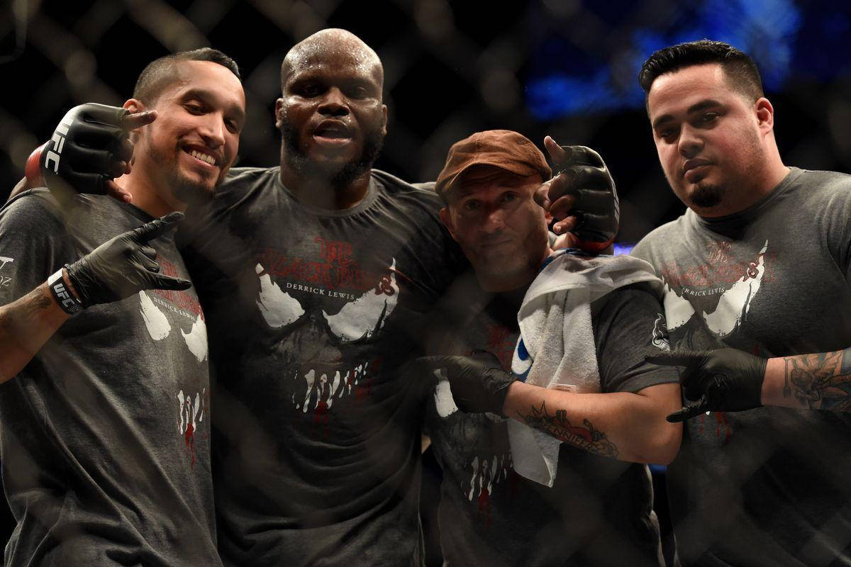 UFC 桌布 壁紙 — 四位微笑的MMA拳手穿著相配的灰色襯衫，在八角籠內舉起戴手套的手合照。