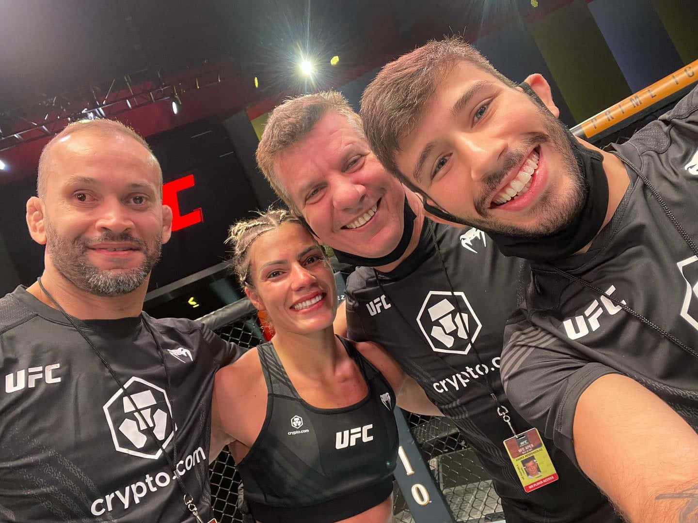 UFC 桌布 壁紙 — 四位微笑的UFC拳手及工作人員在明亮的場館燈光下，於八角籠內一起擺姿勢。